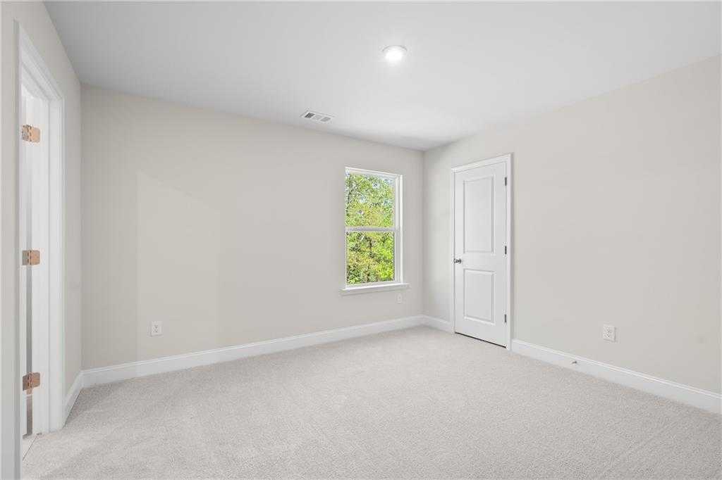 Bright secondary bedroom with neutral walls, plush carpet, and large window in The Hickory B, Buford, Georgia