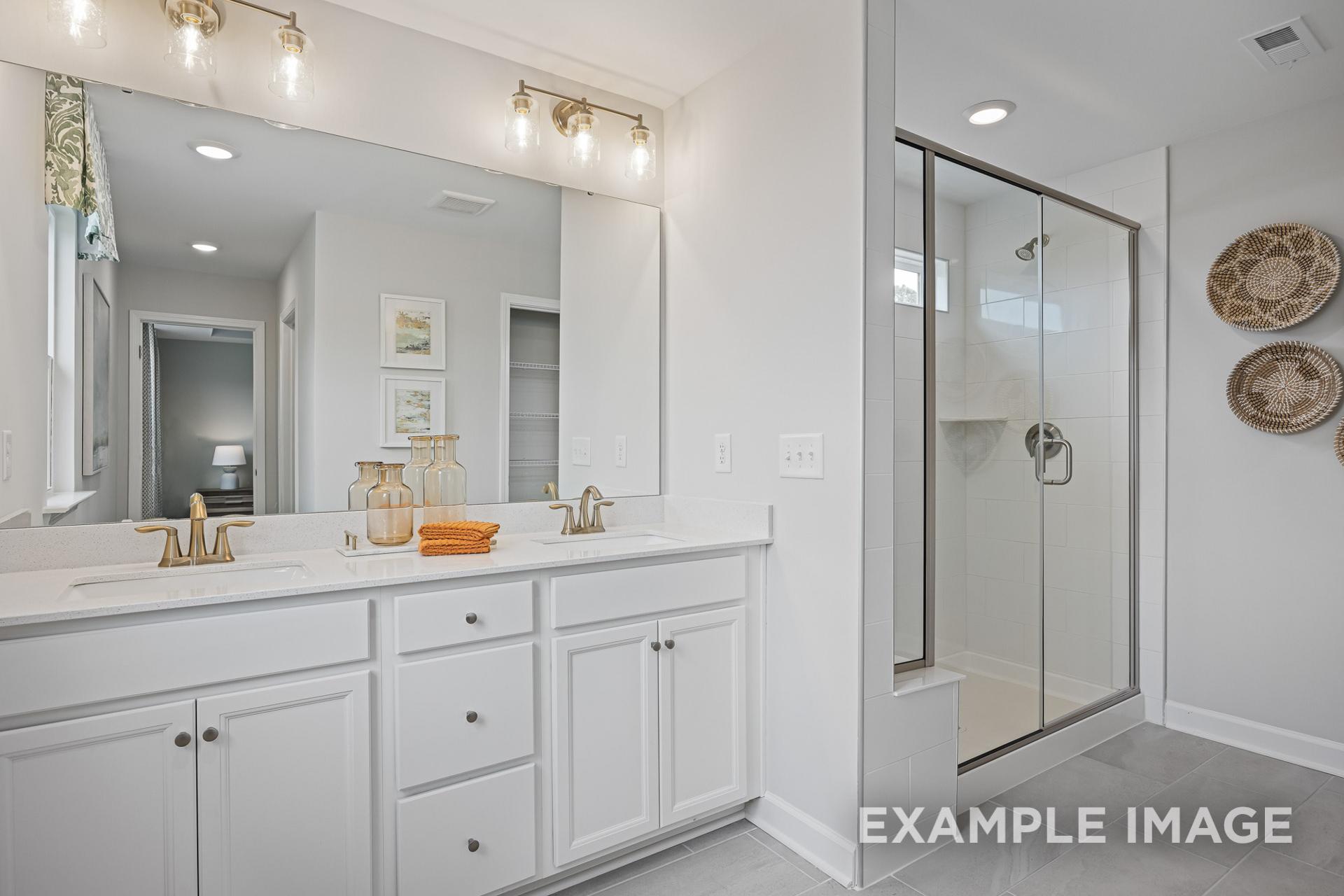 Spacious master bathroom in The Adalynn C with double vanity, frameless glass shower, and woven decor accents