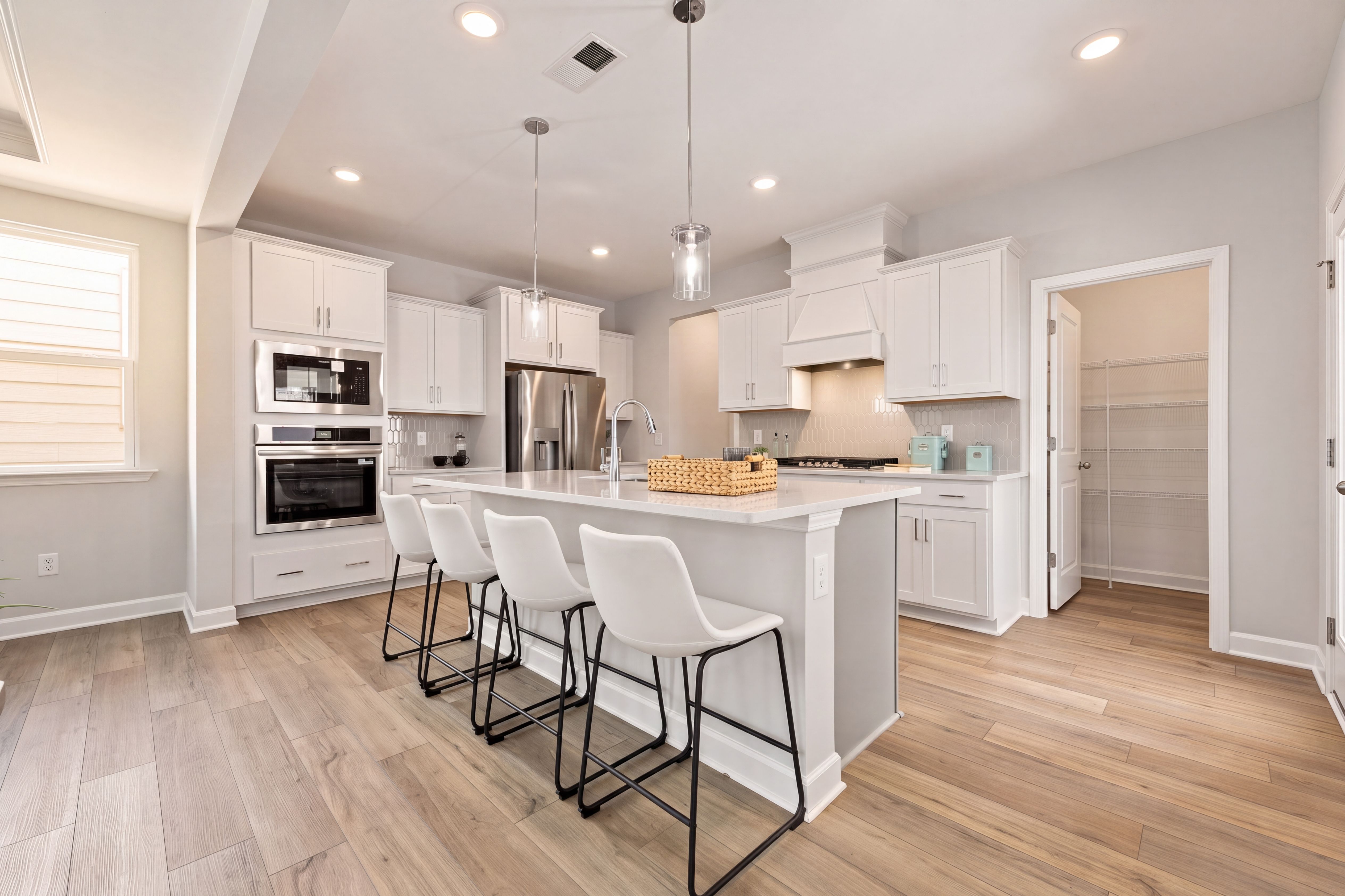 Modern kitchen in The Jordan A featuring white cabinetry, large island with bar seating, and a spacious walk-in pantry.