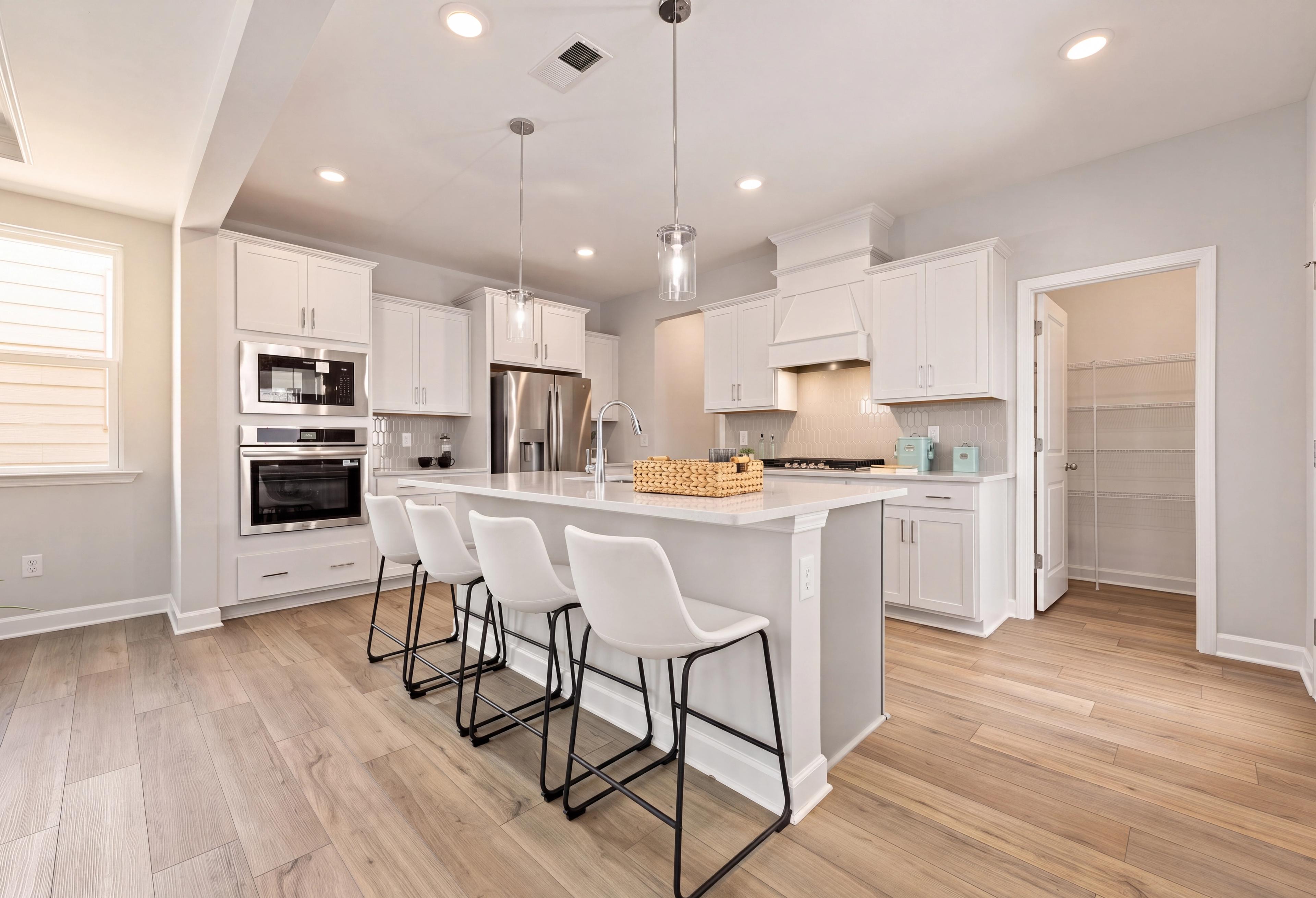 Modern kitchen in The Jordan A featuring white cabinetry, large island with bar seating, and a spacious walk-in pantry.