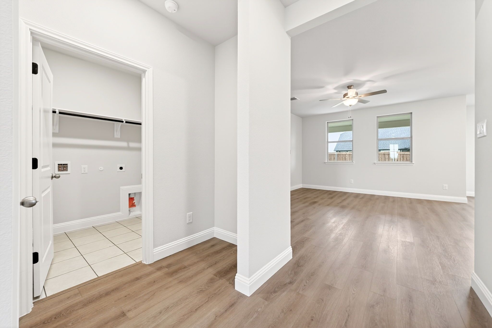 Laundry room entrance with tiled floor adjacent to open-concept living area in The Redbud home design by Davidson Homes.