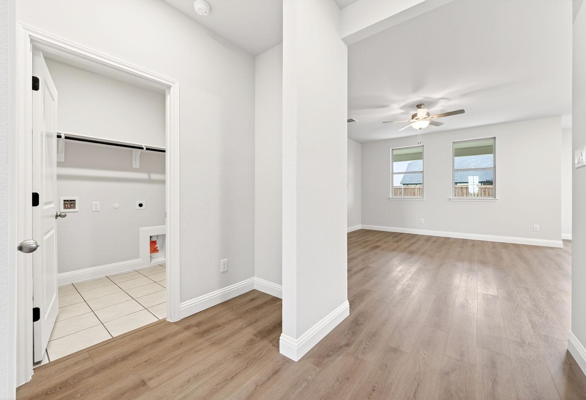 Laundry room entrance with tiled floor adjacent to open-concept living area in The Redbud home design by Davidson Homes.
