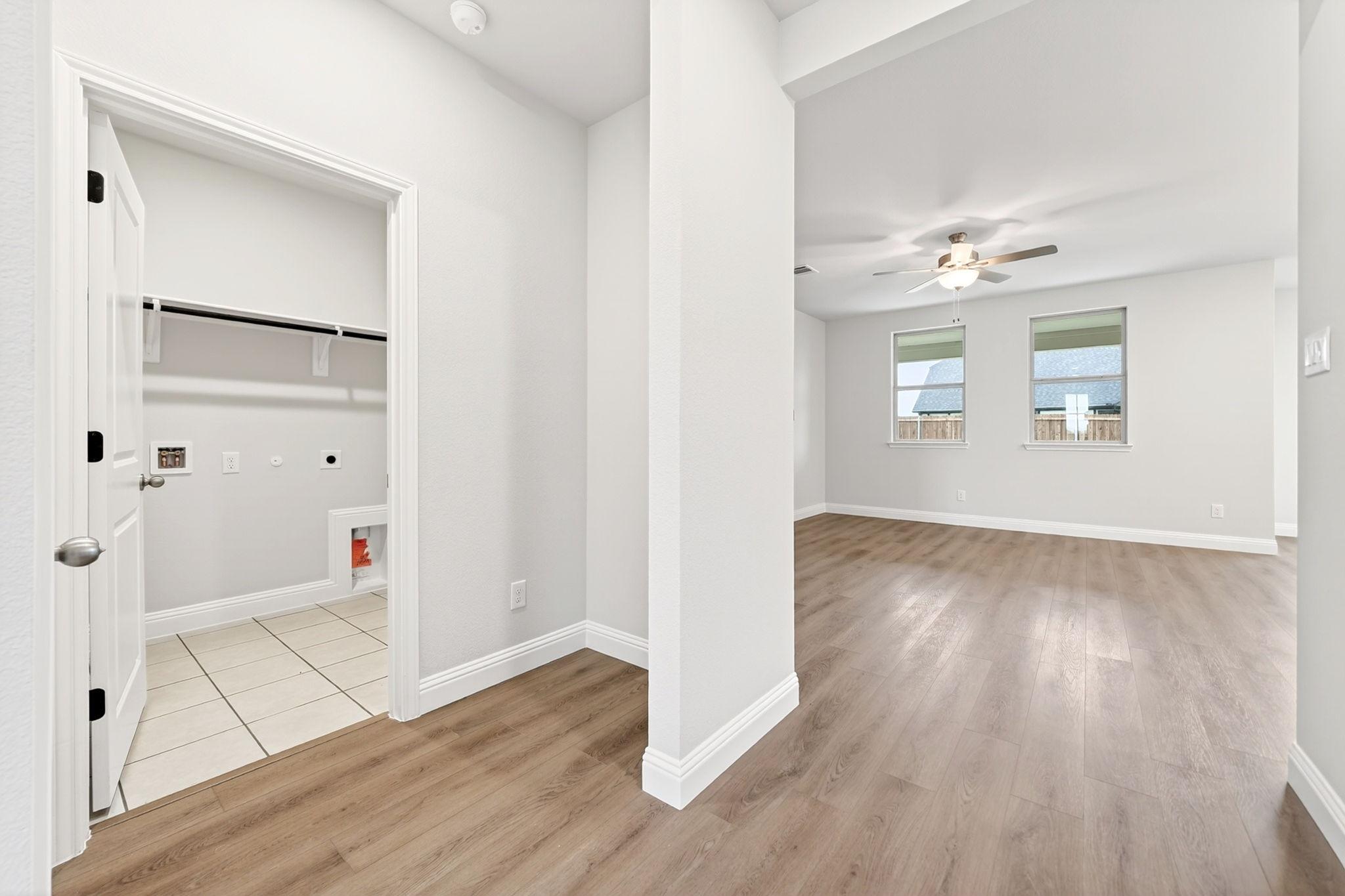 Laundry room entrance with tiled floor adjacent to open-concept living area in The Redbud home design by Davidson Homes.