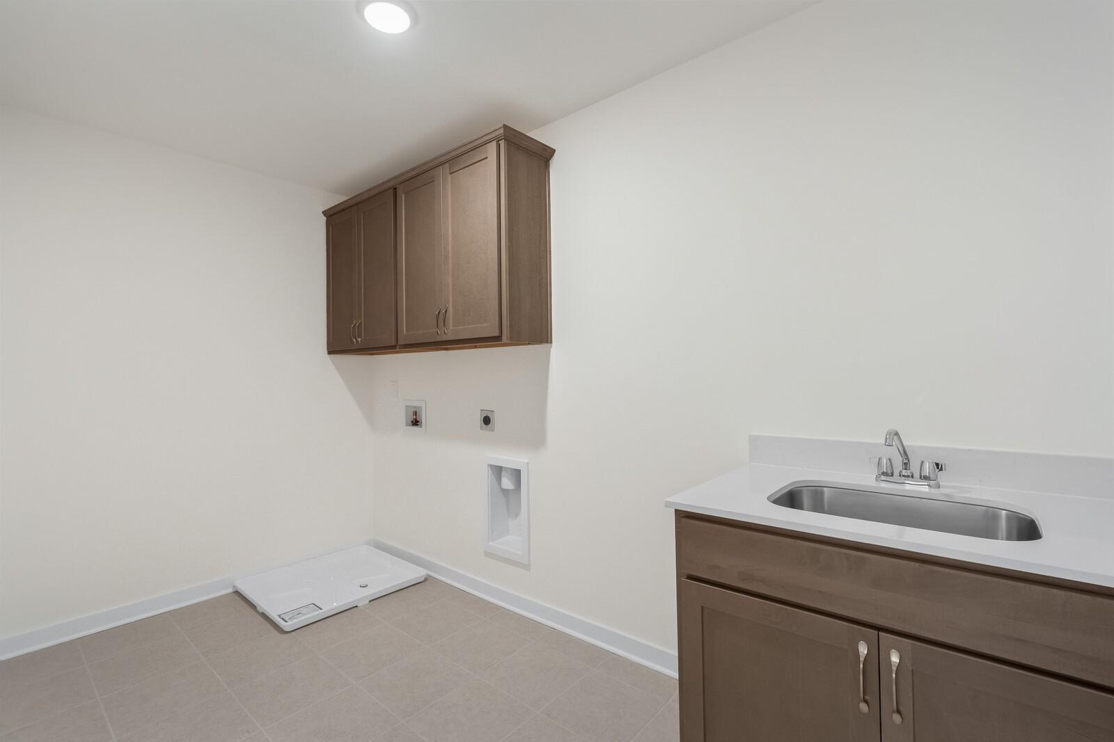 Laundry room with utility sink, cabinets, and washer hookups in The Henry C floor plan by Davidson Homes, Mt. Juliet.