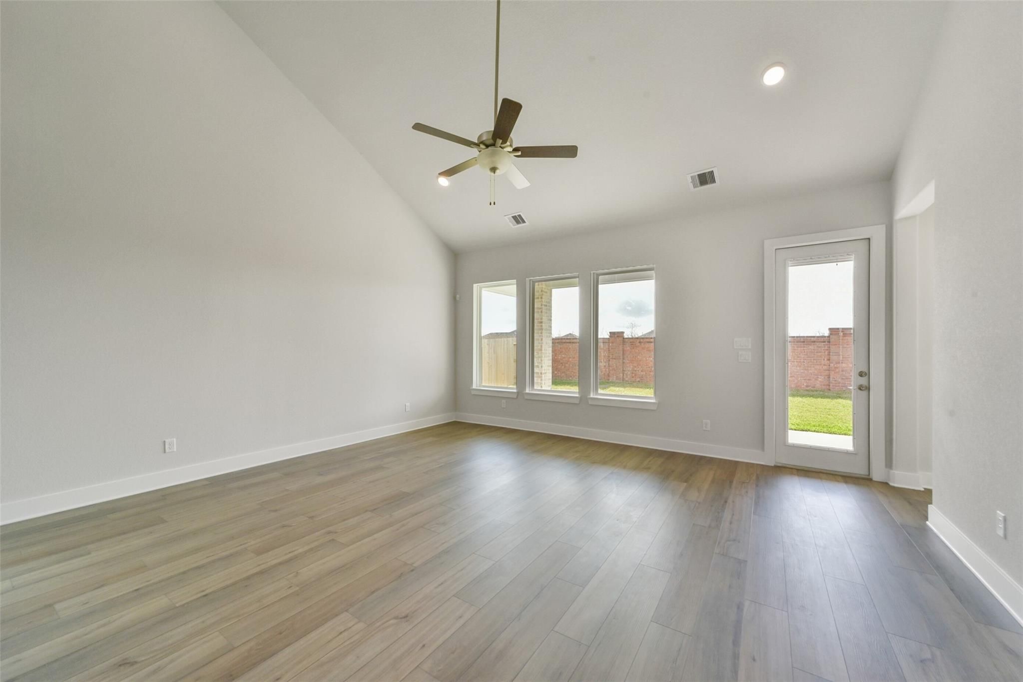 Spacious living room with hardwood floors, large windows, ceiling fan in Davidson Homes The Zion A, Lago Mar, Texas City