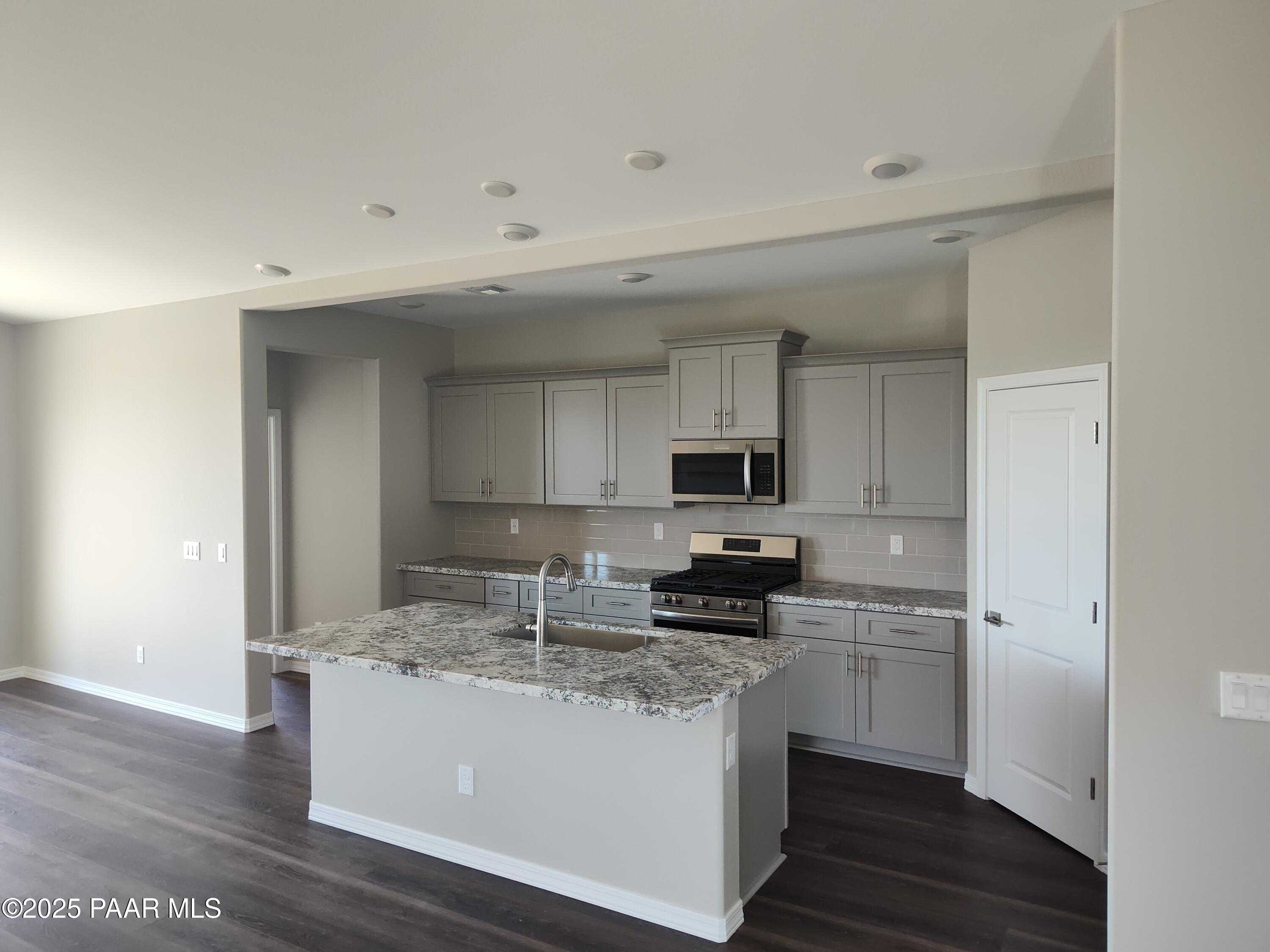 Modern kitchen featuring gray shaker cabinets, granite island sink, stainless steel appliances in Davidson Homes The Frontier A, Prescott Valley, AZ