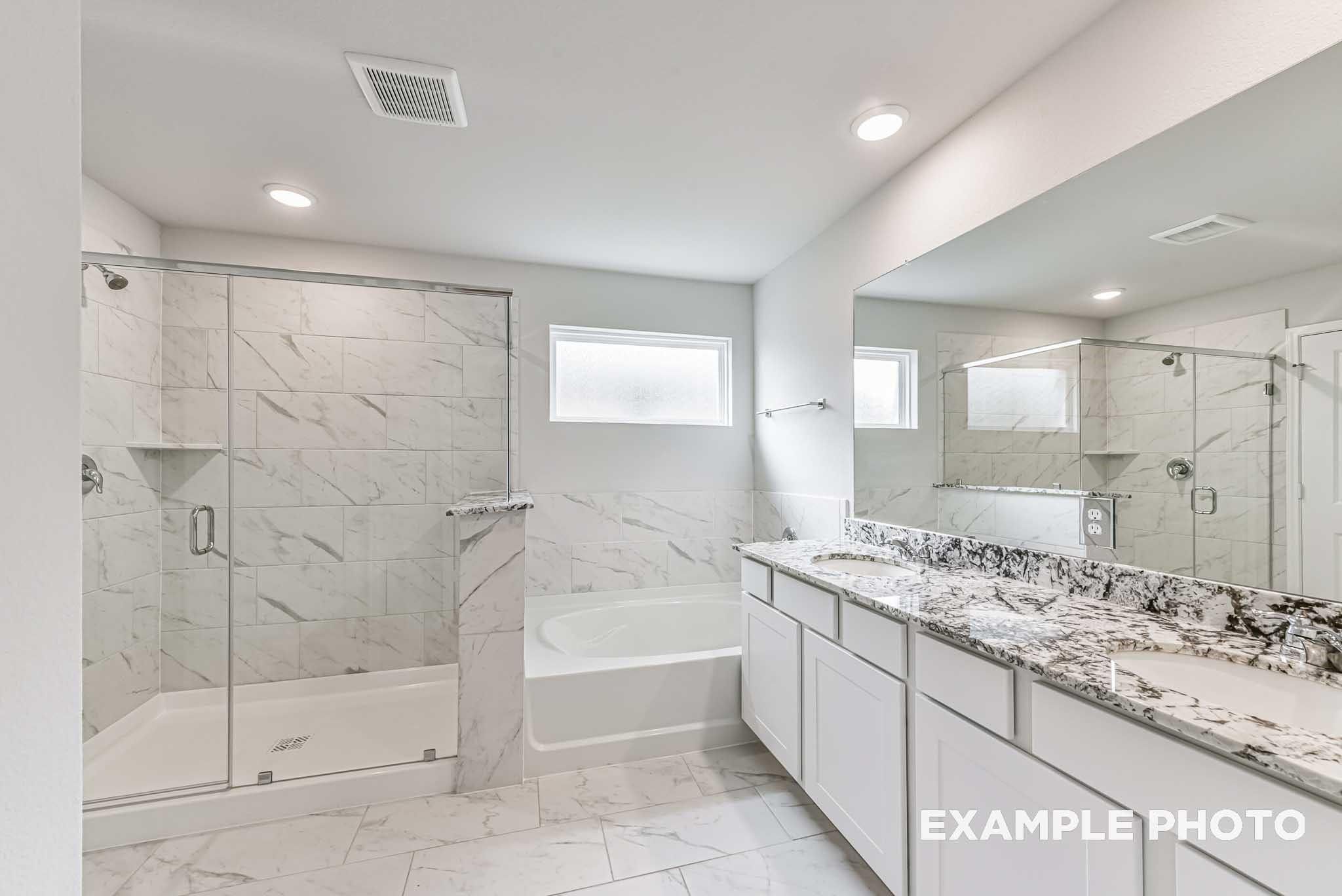 Luxurious master bathroom with glass shower, soaking tub, and quartz double vanity in Davidson Homes The Riviera A, Rosharon, Texas