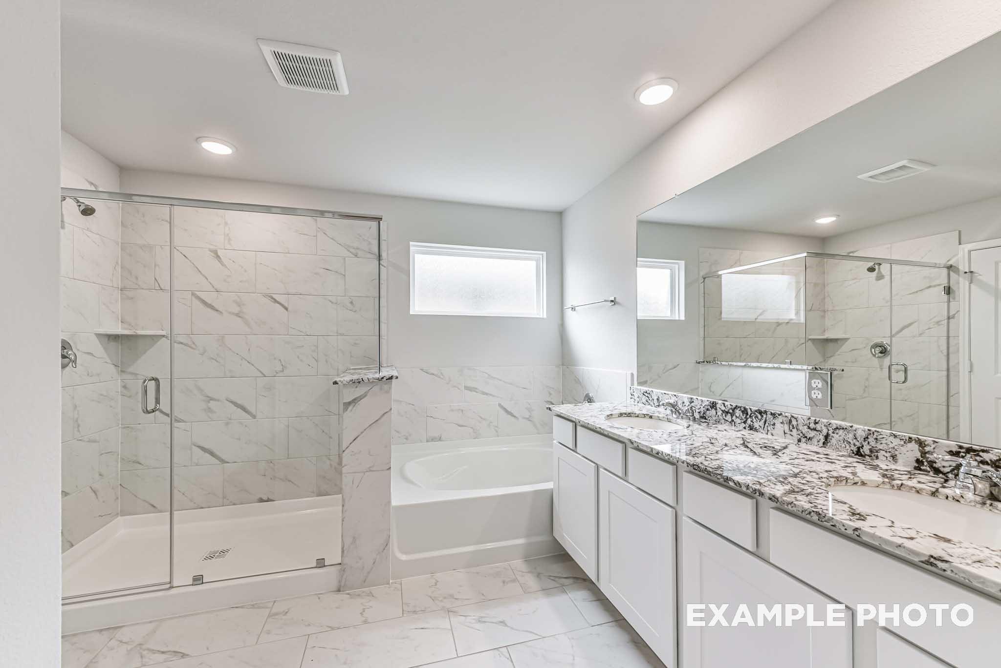 Luxurious master bathroom with glass shower, soaking tub, and quartz double vanity in Davidson Homes The Riviera A, Rosharon, Texas