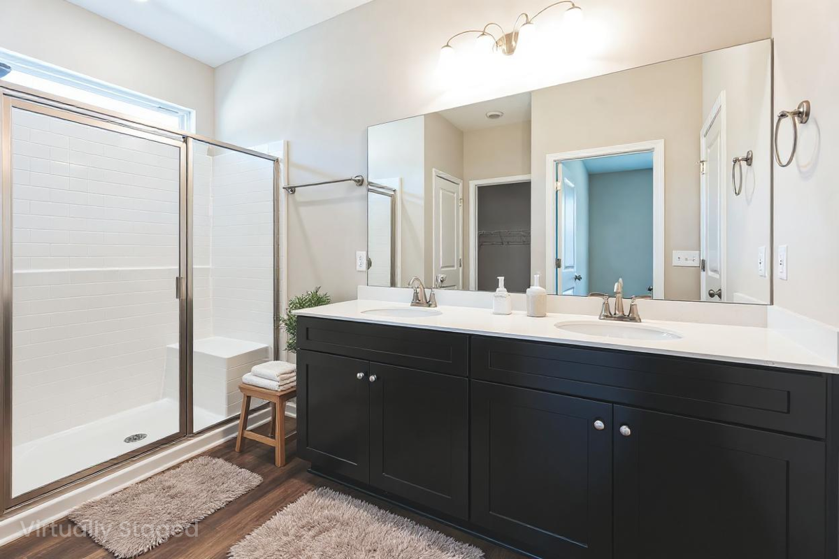 Spacious bathroom at Heatherbrook in Phenix City AL featuring double black vanity, glass walk-in shower, and neutral tones by Evermore Homes