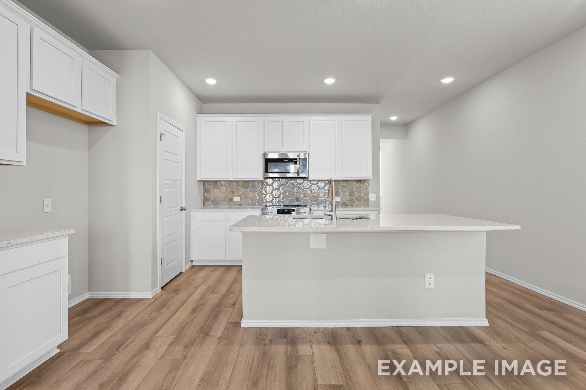 Modern kitchen with white cabinets, quartz island, and honeycomb backsplash in Davidson Homes Colorado G floor plan.