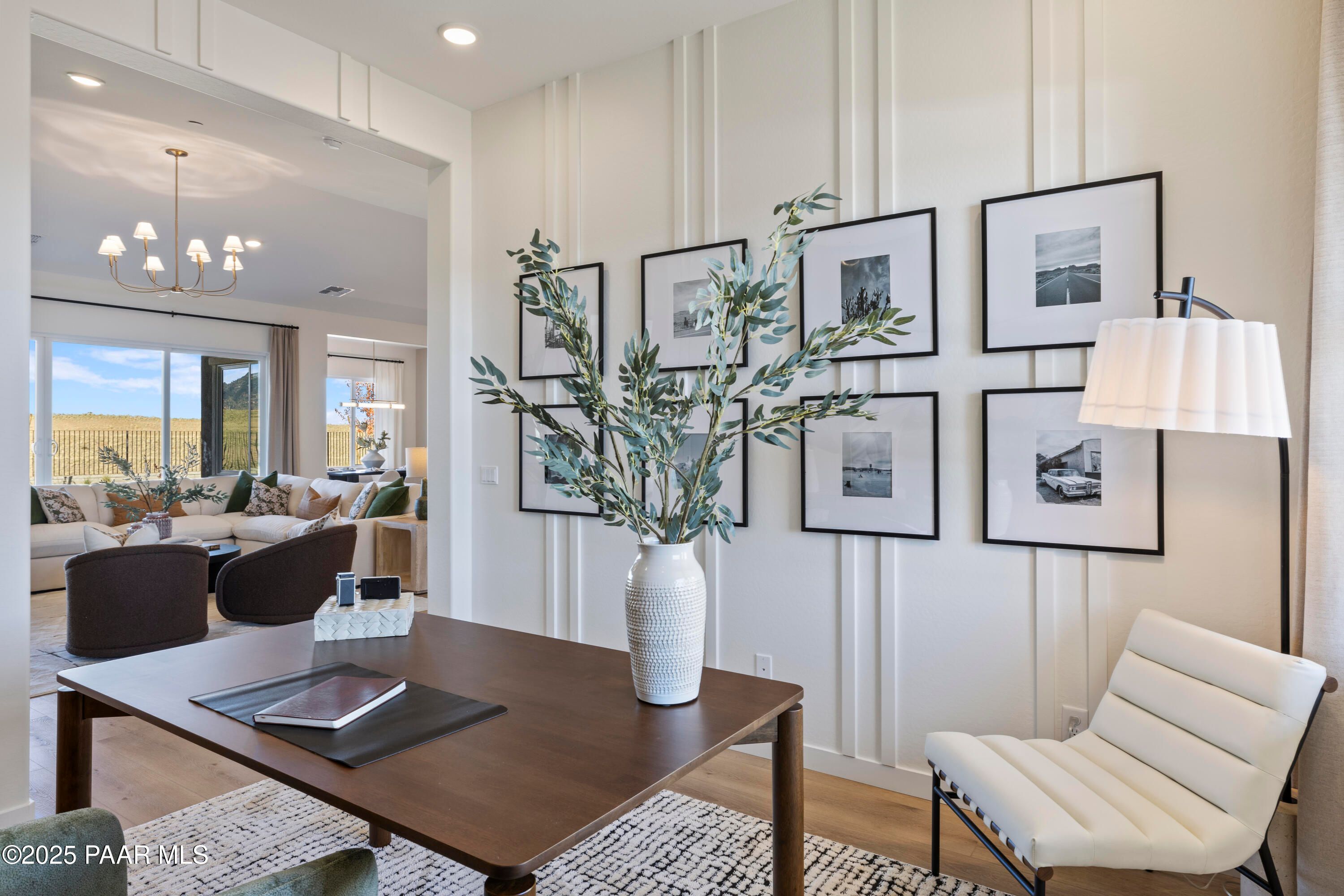 Stylish home office with wooden desk, white chair, olive branches, and framed art in Davidson Homes The Blaze D, Prescott AZ