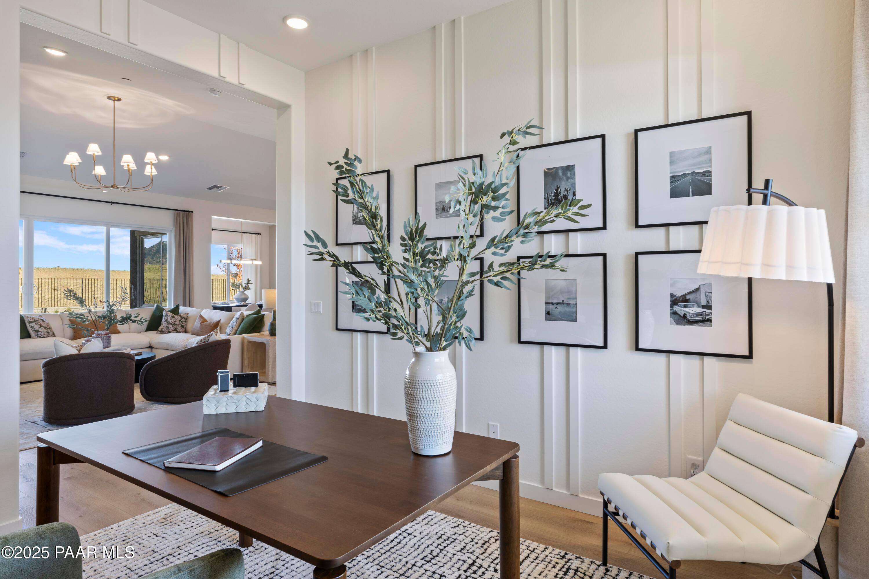 Stylish home office with wooden desk, white chair, olive branches, and framed art in Davidson Homes The Blaze D, Prescott AZ