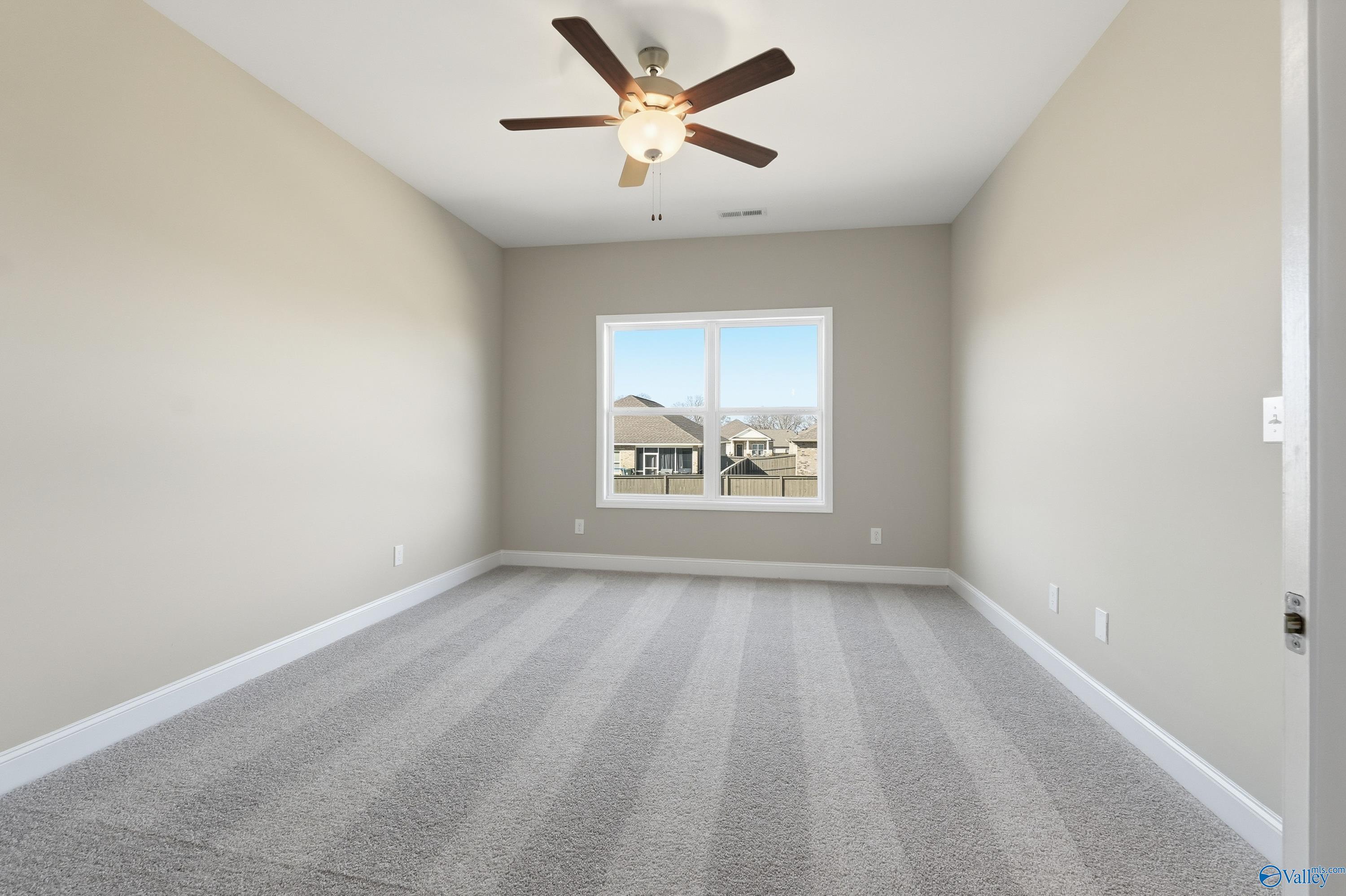 Bright secondary bedroom with ceiling fan, beige walls, and window view in Davidson Homes The Franklin C, New Market, Alabama