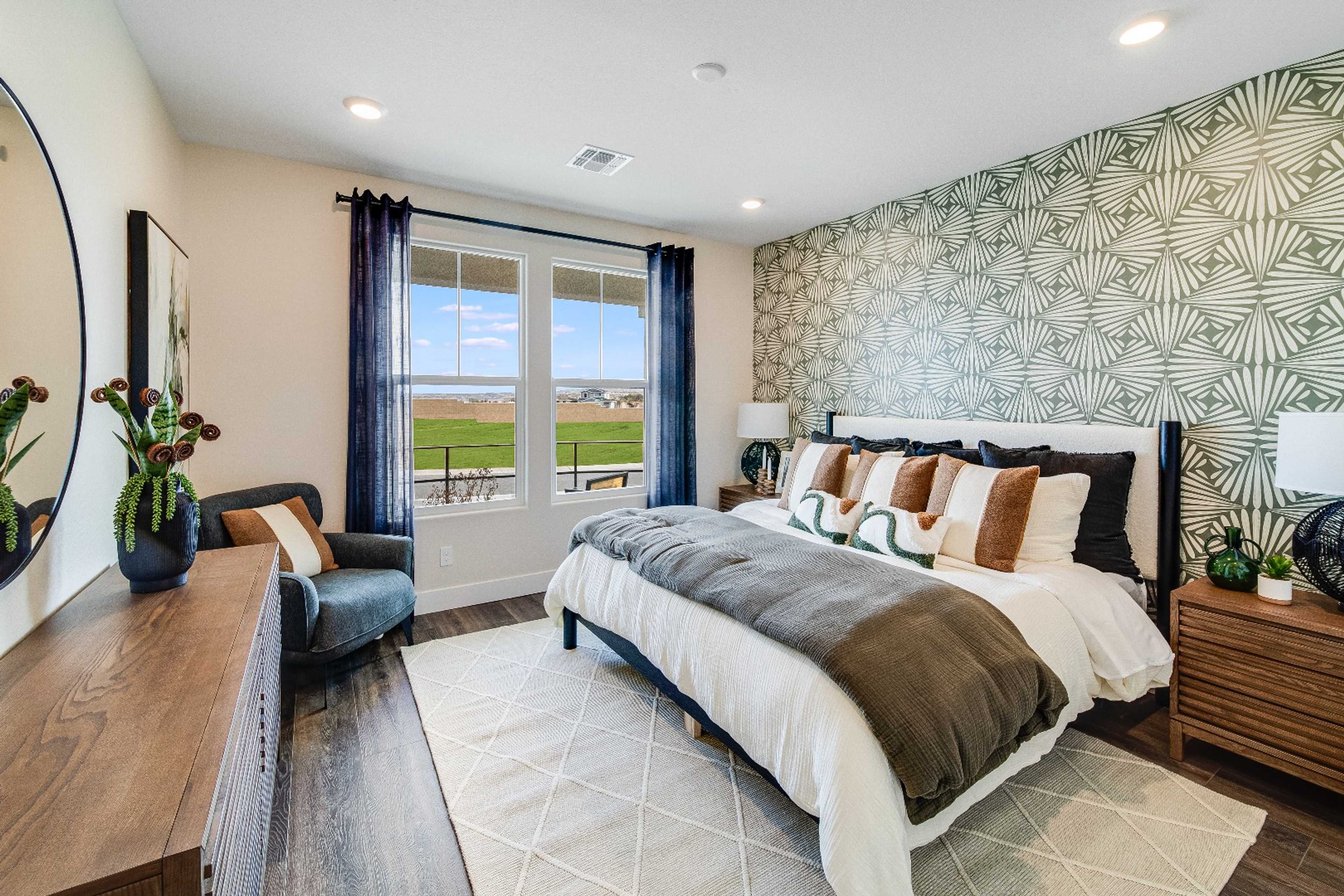 Spacious master bedroom in South Ranch Western Collection, Prescott AZ featuring king bed, geometric wallpaper, wooden nightstands, and golf course view
