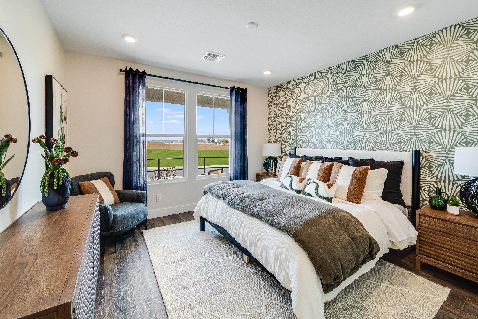 Spacious master bedroom in South Ranch Western Collection, Prescott AZ featuring king bed, geometric wallpaper, wooden nightstands, and golf course view