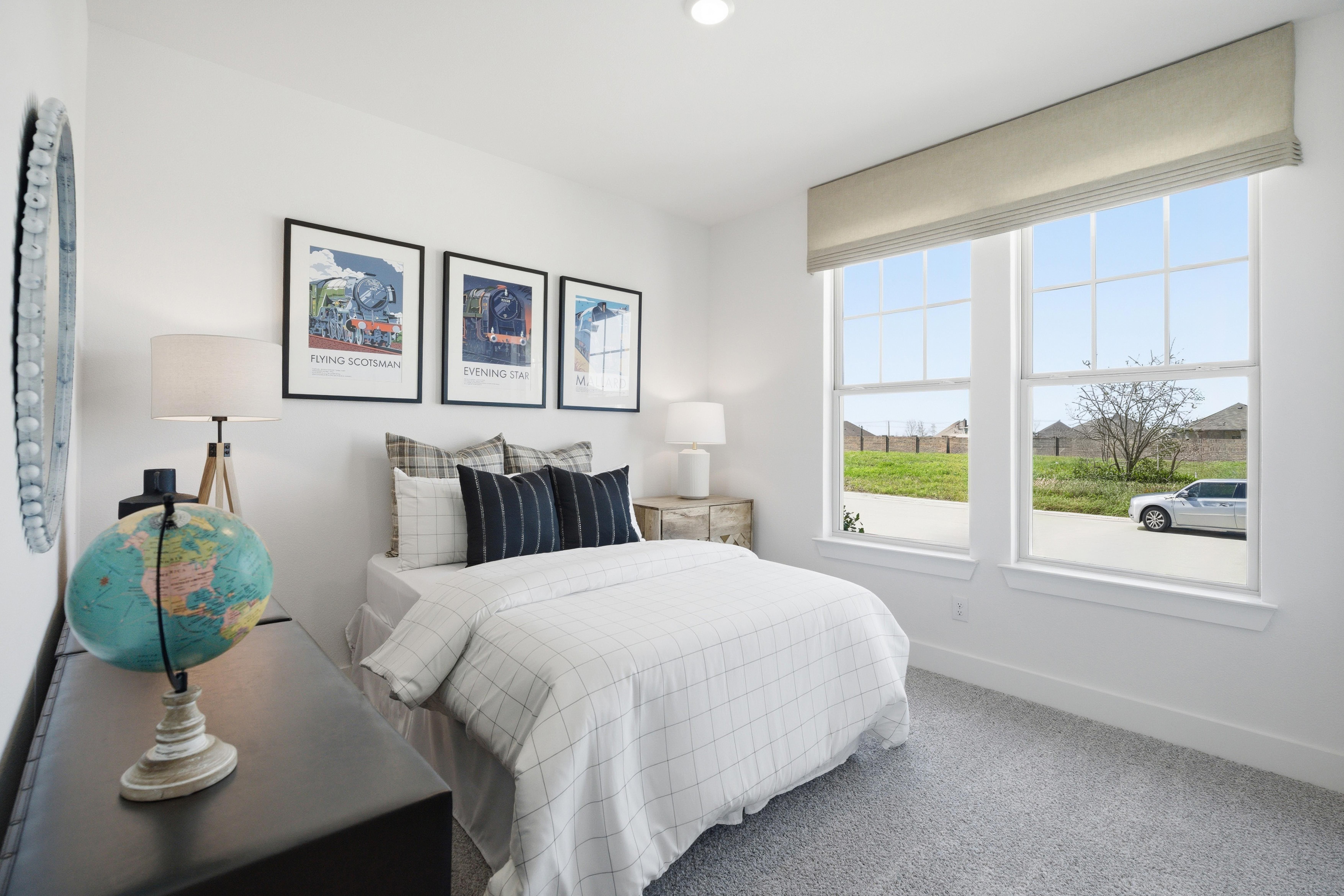 Cozy bedroom in Mercer Meadows Royse City TX with twin bed, white duvet, train art, globe decor, and window views of neighborhood