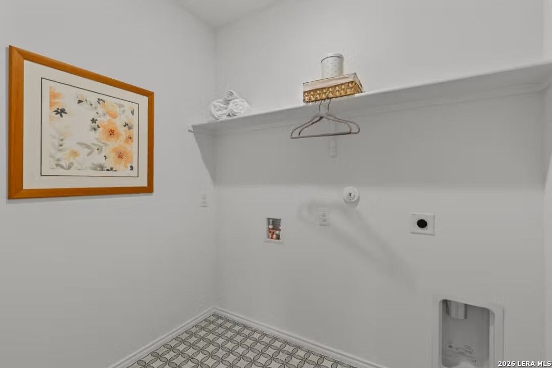 Bright laundry room with floral artwork, built-in shelves, utility sink in Davidson Homes The Daphne H, Seguin, Texas