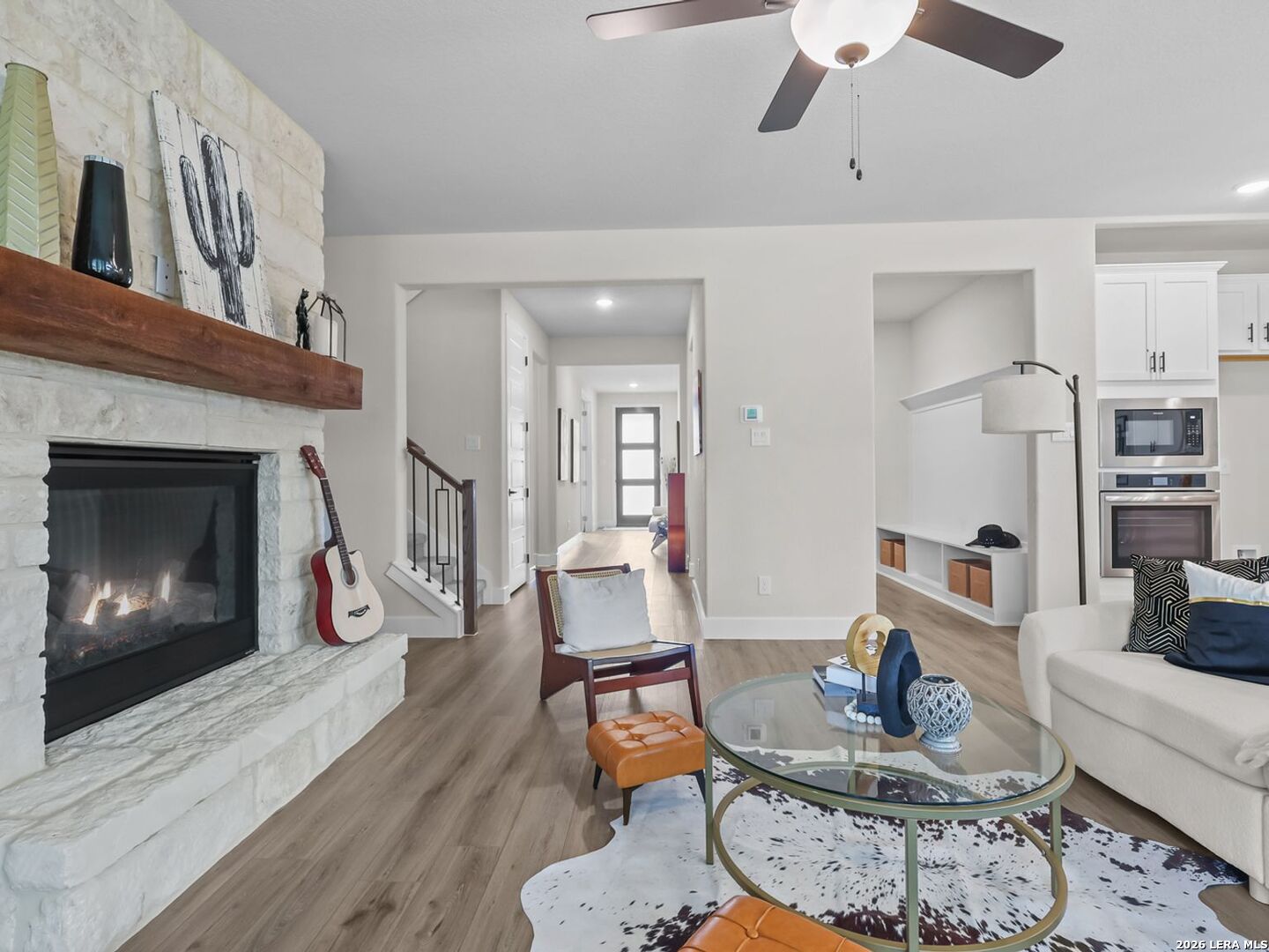 Living room with stone fireplace in The Belmont H floor plan by Davidson Homes in Potranco Oaks, Castroville, Texas.