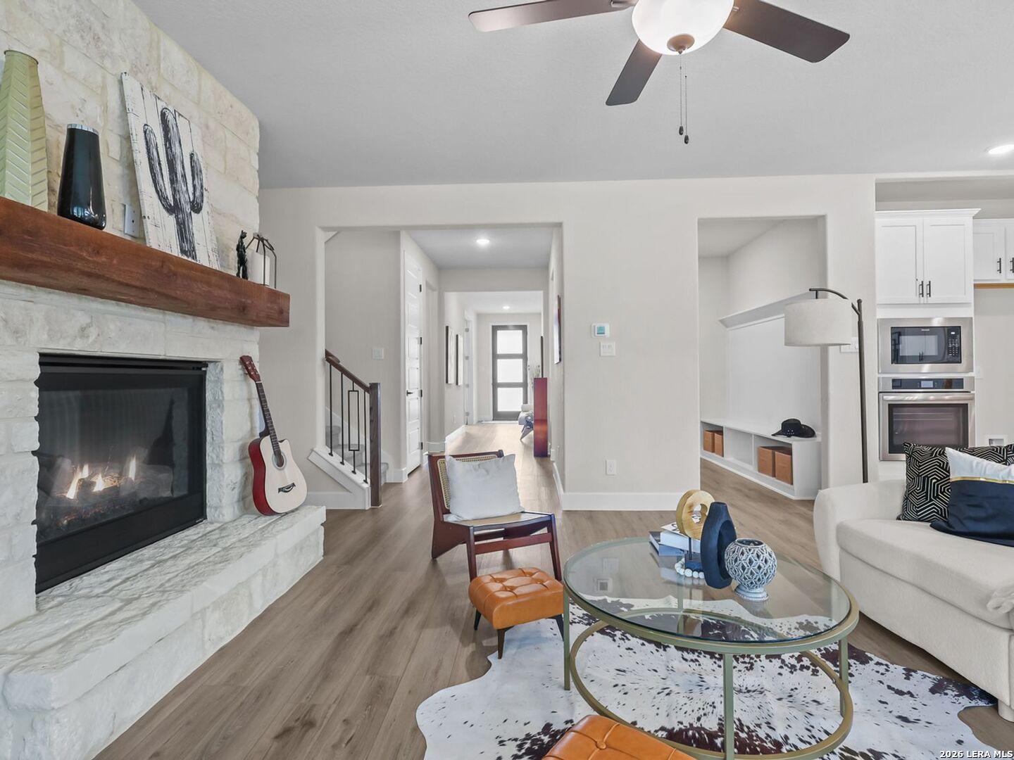 Living room with stone fireplace in The Belmont H floor plan by Davidson Homes in Potranco Oaks, Castroville, Texas.