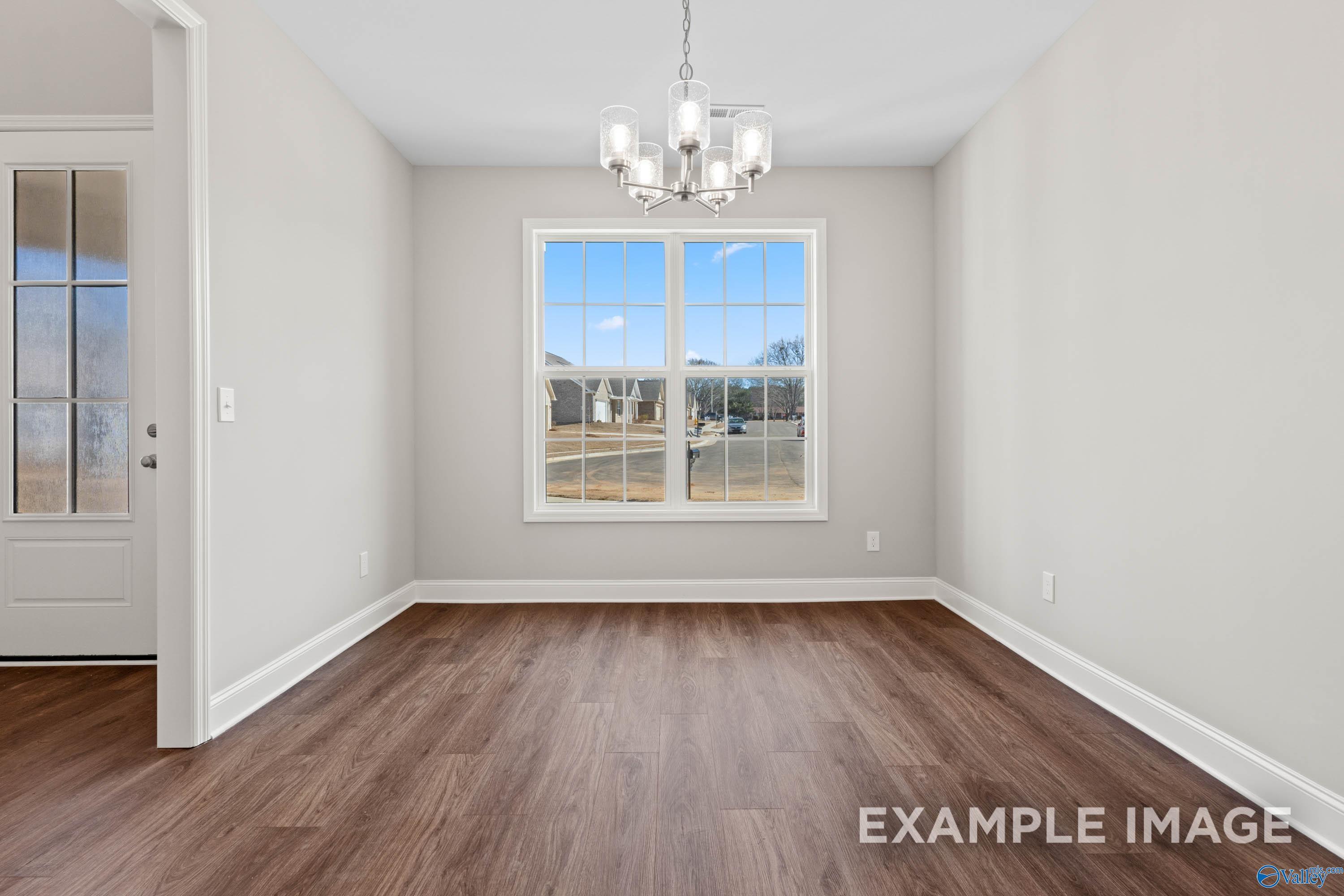 Bright dining room with modern chandelier and wood-look floors in The Madison D floor plan at Evergreen Mill, Madison, AL.