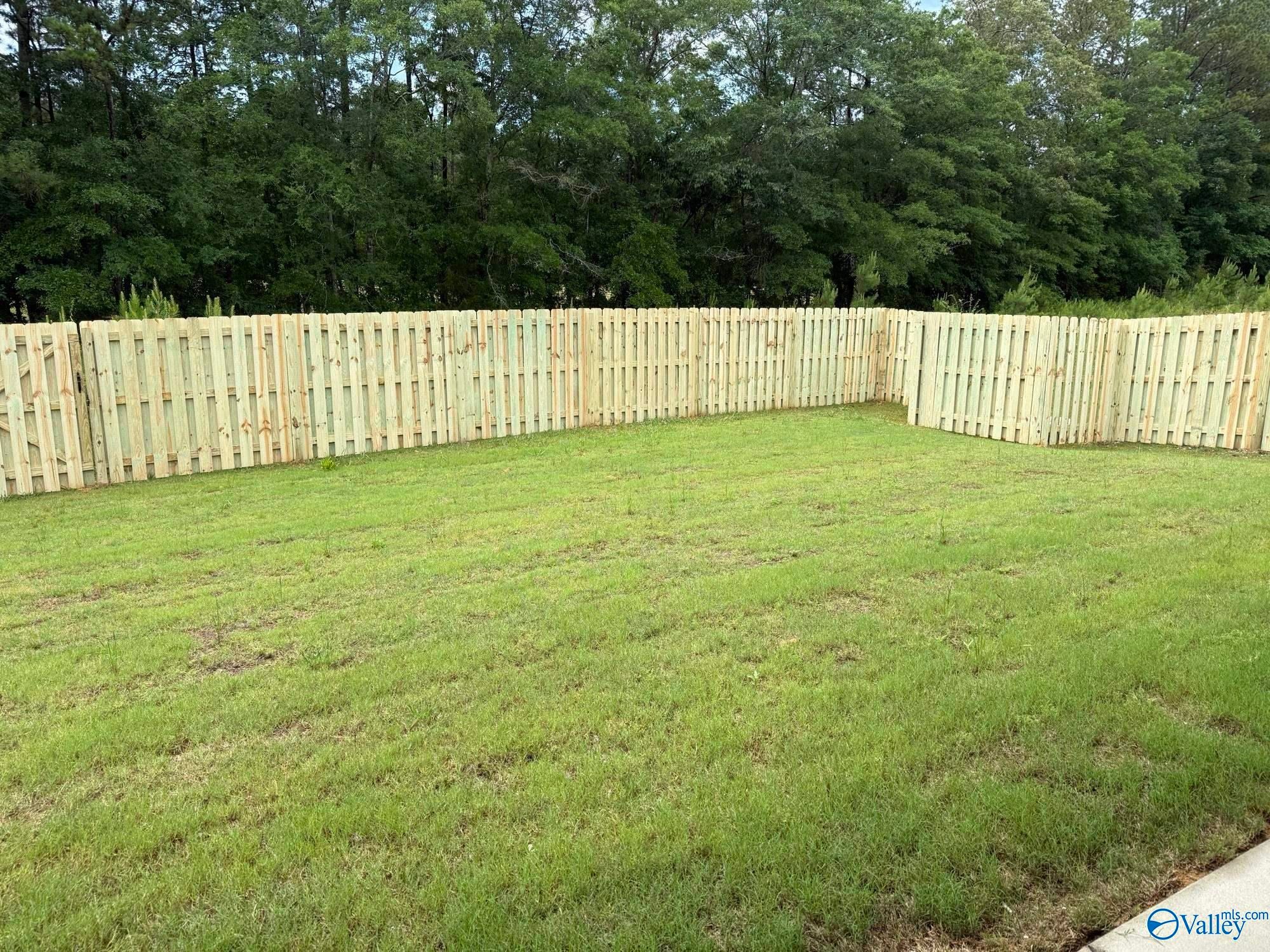 Private fenced backyard with lush green lawn at The Montgomery B home in Cain Park, Hartselle, Alabama.