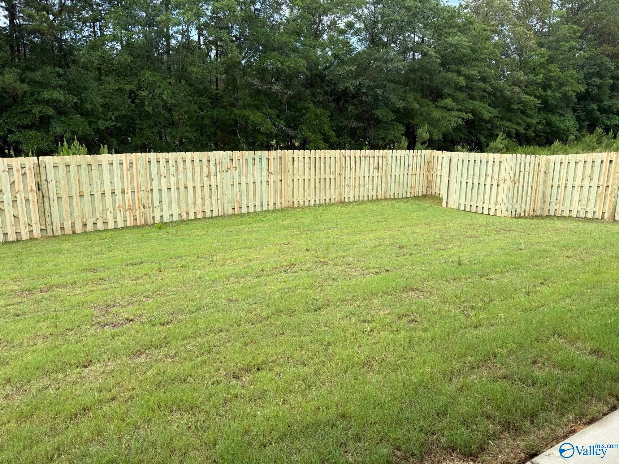 Private fenced backyard with lush green lawn at The Montgomery B home in Cain Park, Hartselle, Alabama.