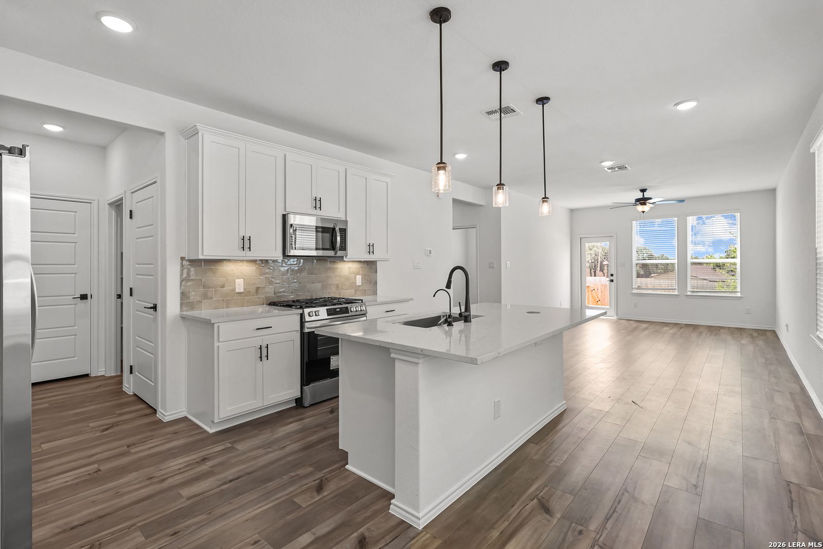 Modern kitchen with white cabinets, quartz island, and stainless appliances in The Gillian C floor plan, San Antonio, TX.