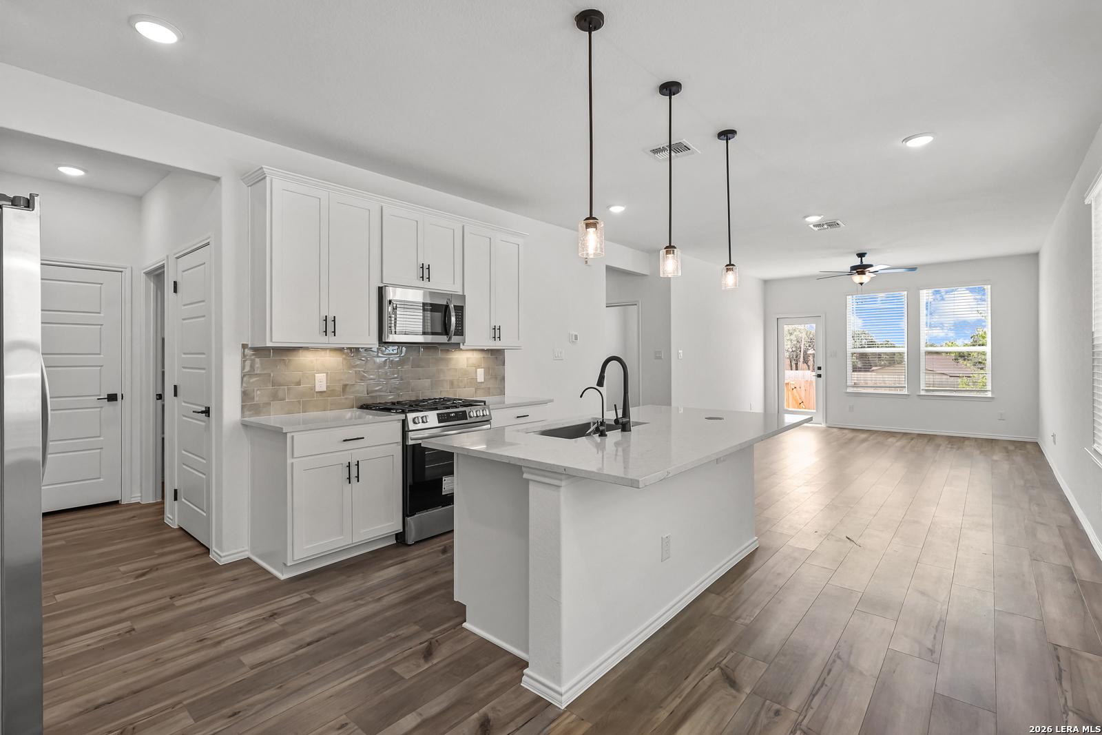 Modern kitchen with white cabinets, quartz island, and stainless appliances in The Gillian C floor plan, San Antonio, TX.