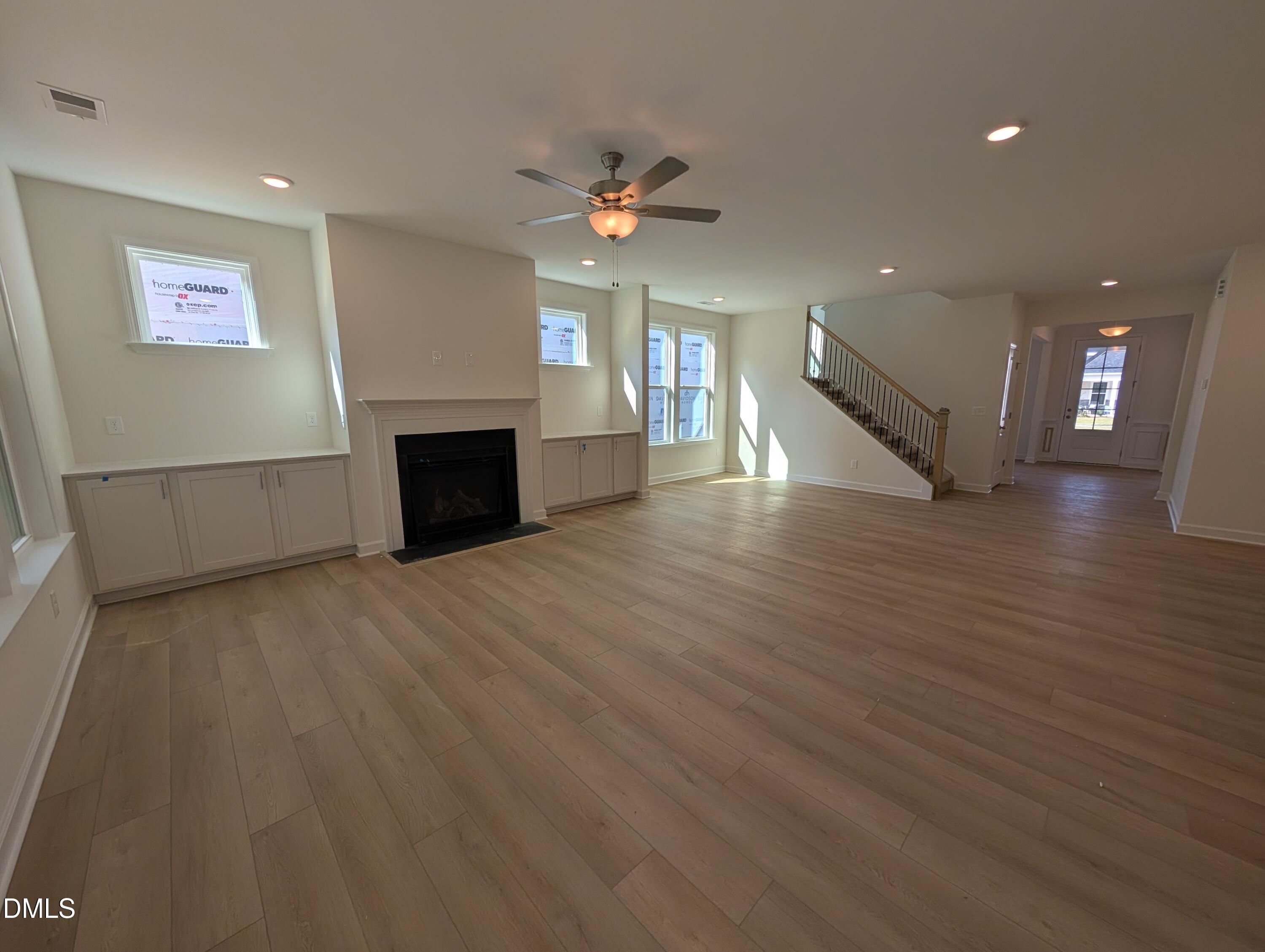 Open-concept great room with fireplace, built-in cabinetry, luxury vinyl plank floors, and staircase in Davidson Homes Magnolia A, Wendell Ridge