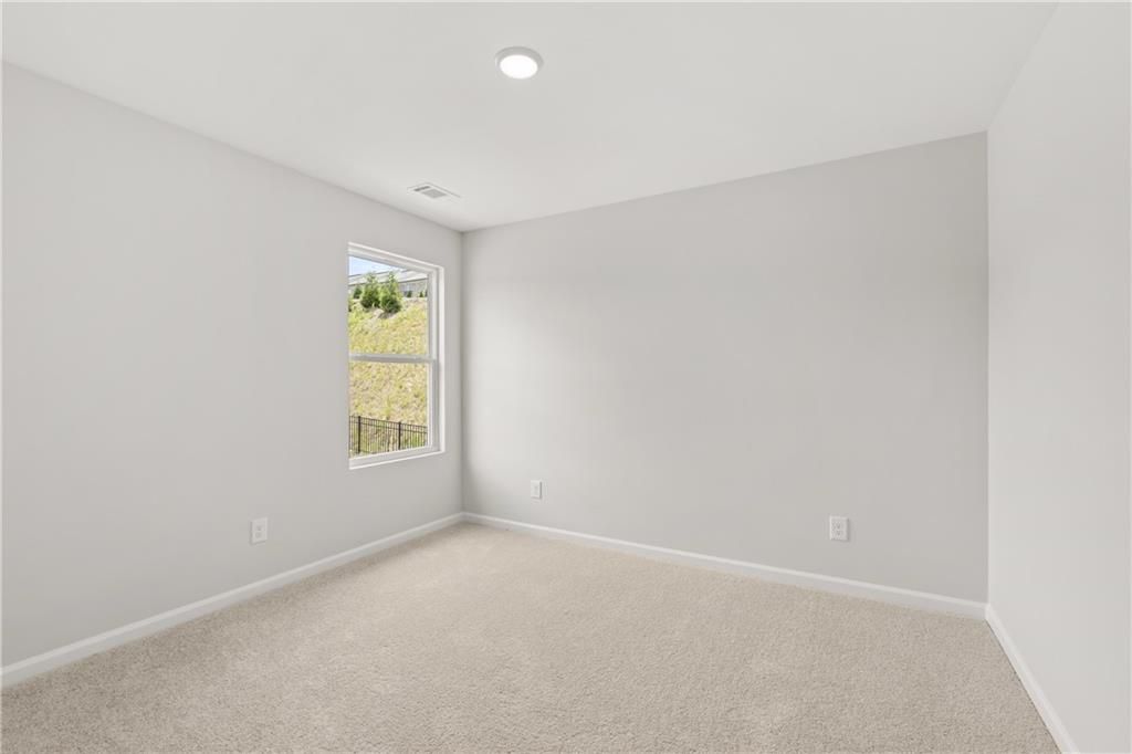 Bright, carpeted bedroom with neutral walls in The Burton A floor plan at The Bluffs in Canton, Georgia.