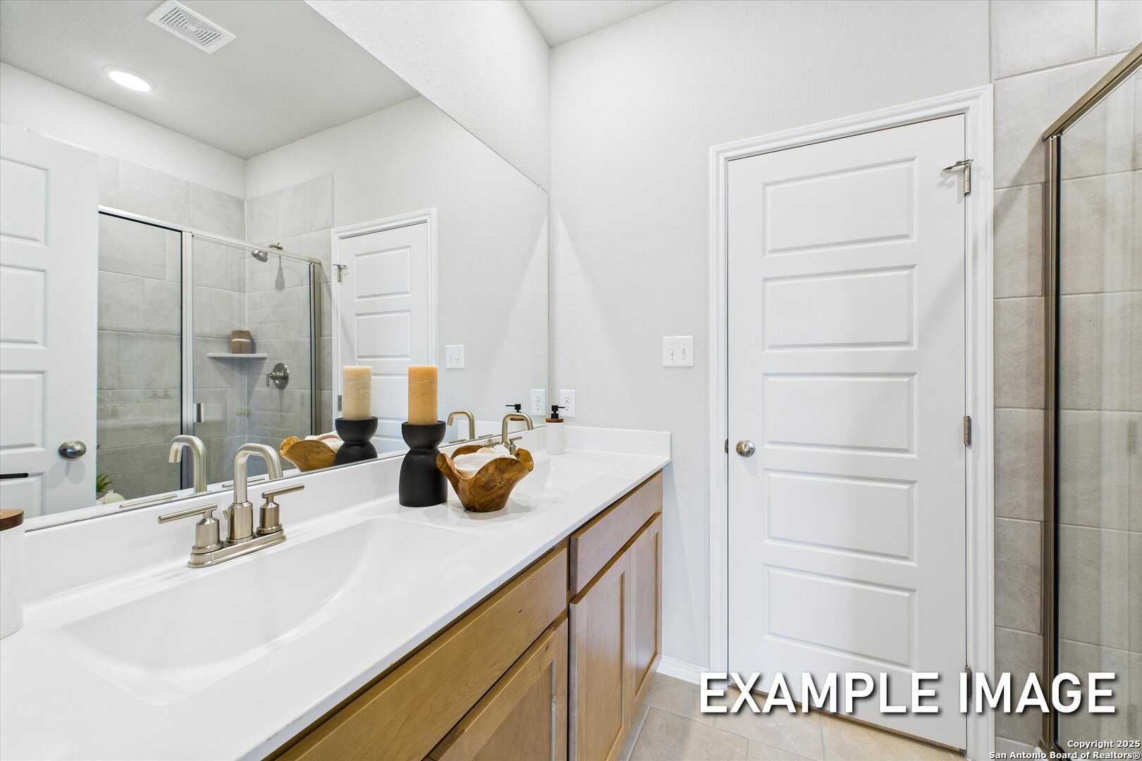 Modern master bathroom with double vanity sinks, large mirror, and walk-in shower in Davidson Homes The Sabine C, San Antonio