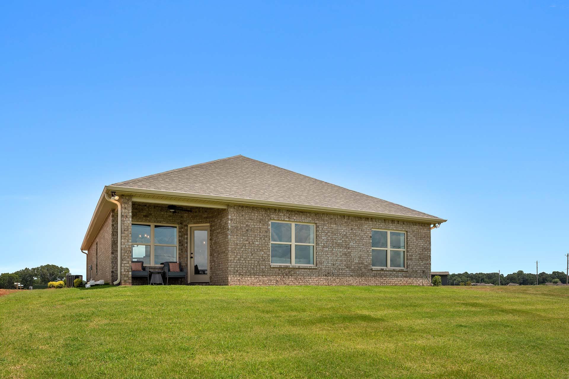 Brick home exterior at Heritage Lakes in New Market, Alabama with covered side porch, large windows and lush green lawn