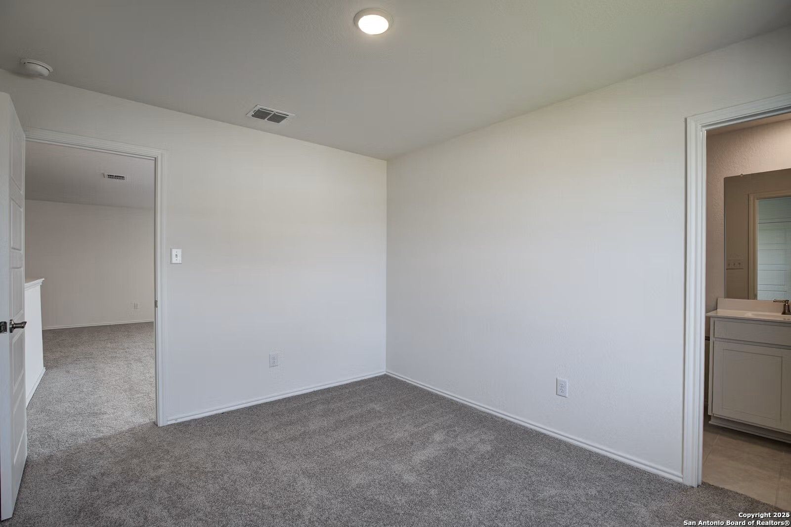 Bright secondary bedroom with gray carpet and attached bath vanity in Davidson Homes The Douglas B, Seguin, Texas