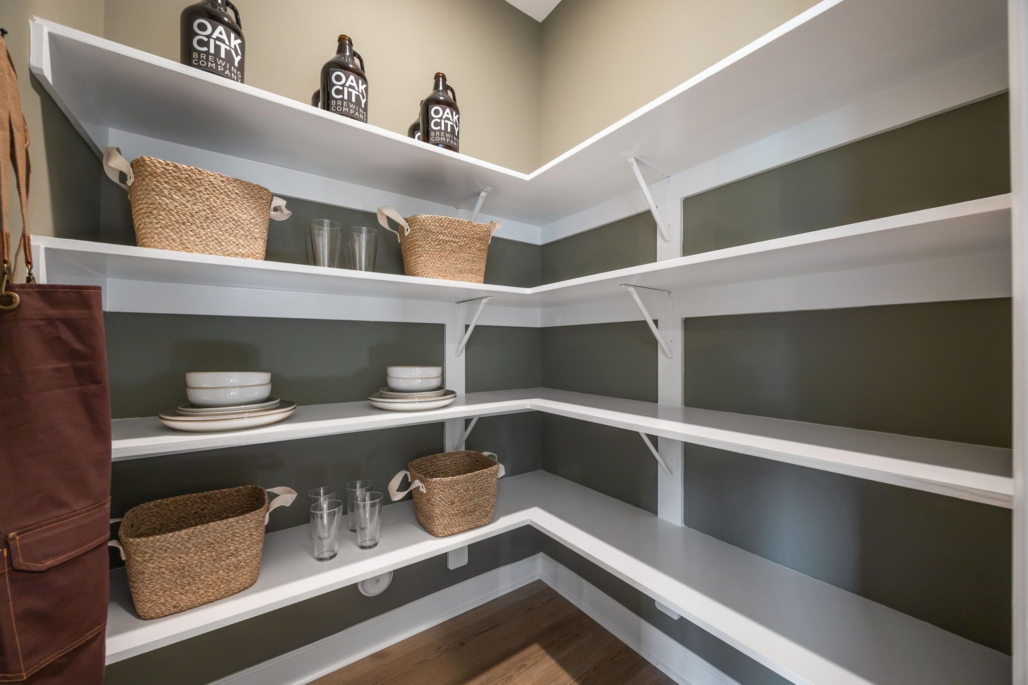 Spacious walk-in pantry at Camden Park in Knightdale NC with white shelves, wicker baskets, oak bottles and dishware