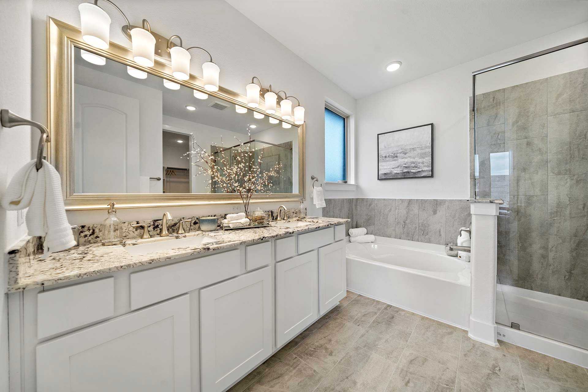 Luxury master bathroom in Sierra Vista Rosharon TX with white shaker cabinets, freestanding tub, glass shower, gold mirror by Davidson Homes