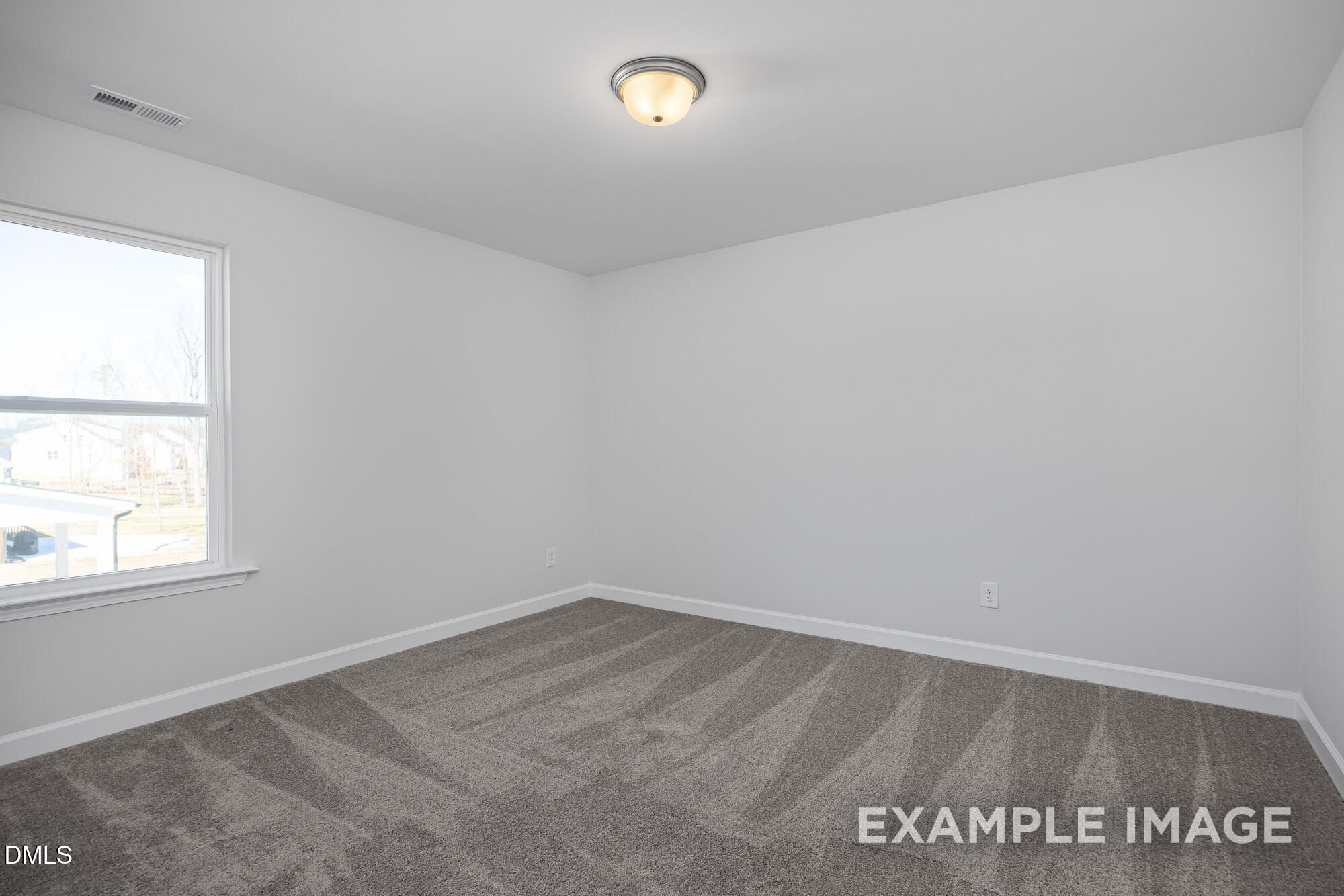 Bright empty bedroom with white walls, large window, ceiling light, and gray carpet in Davidson Homes The Cypress B II, Angier, NC