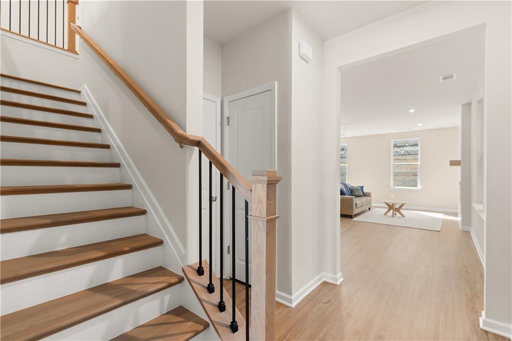 Elegant wooden staircase with black iron balusters in open foyer to living room, Davidson Homes The Marion B, Kennesaw, GA