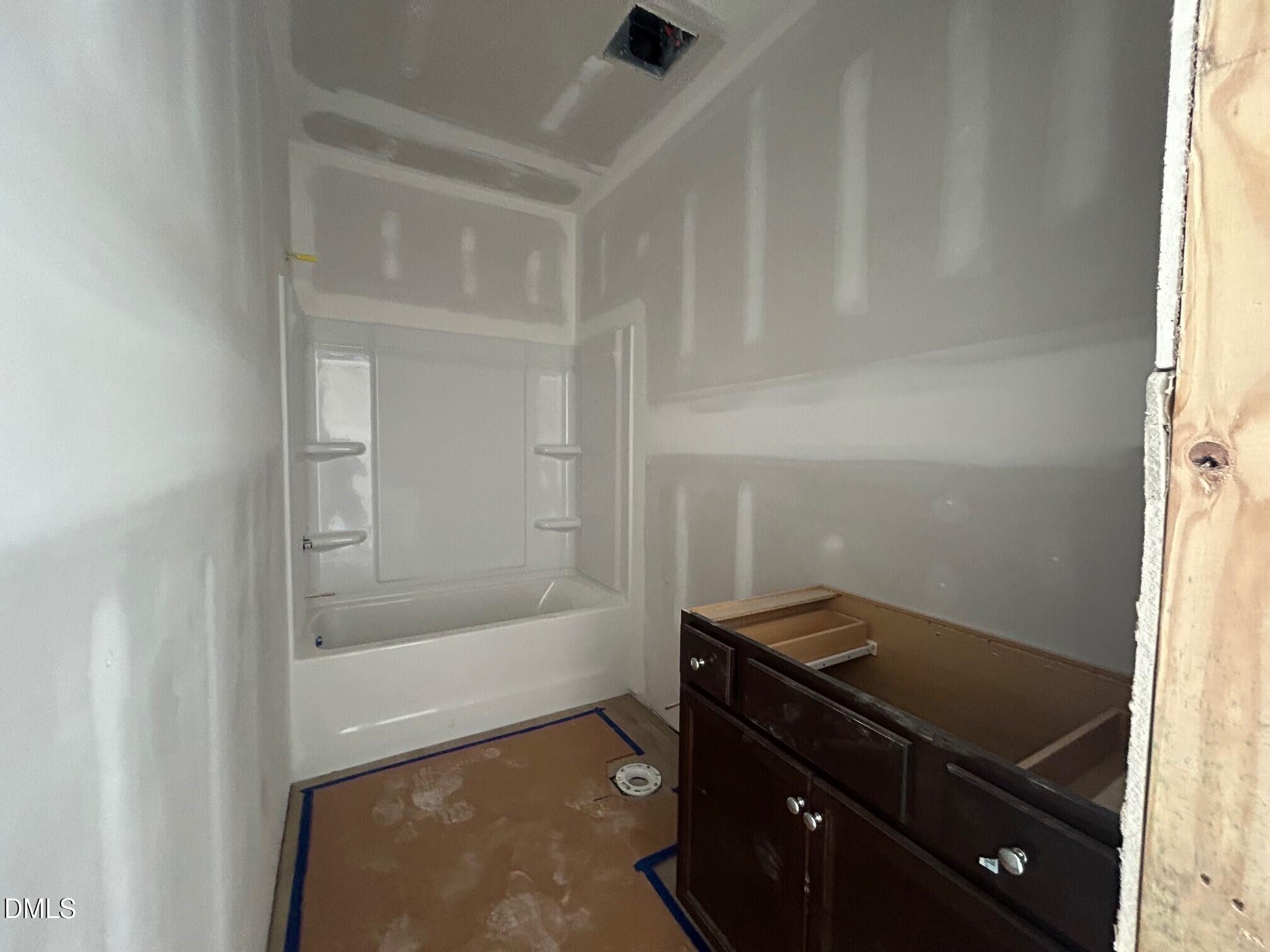 Secondary bathroom with white tub-shower combo and wooden vanity in Davidson Homes The Daphne D, Lillington NC