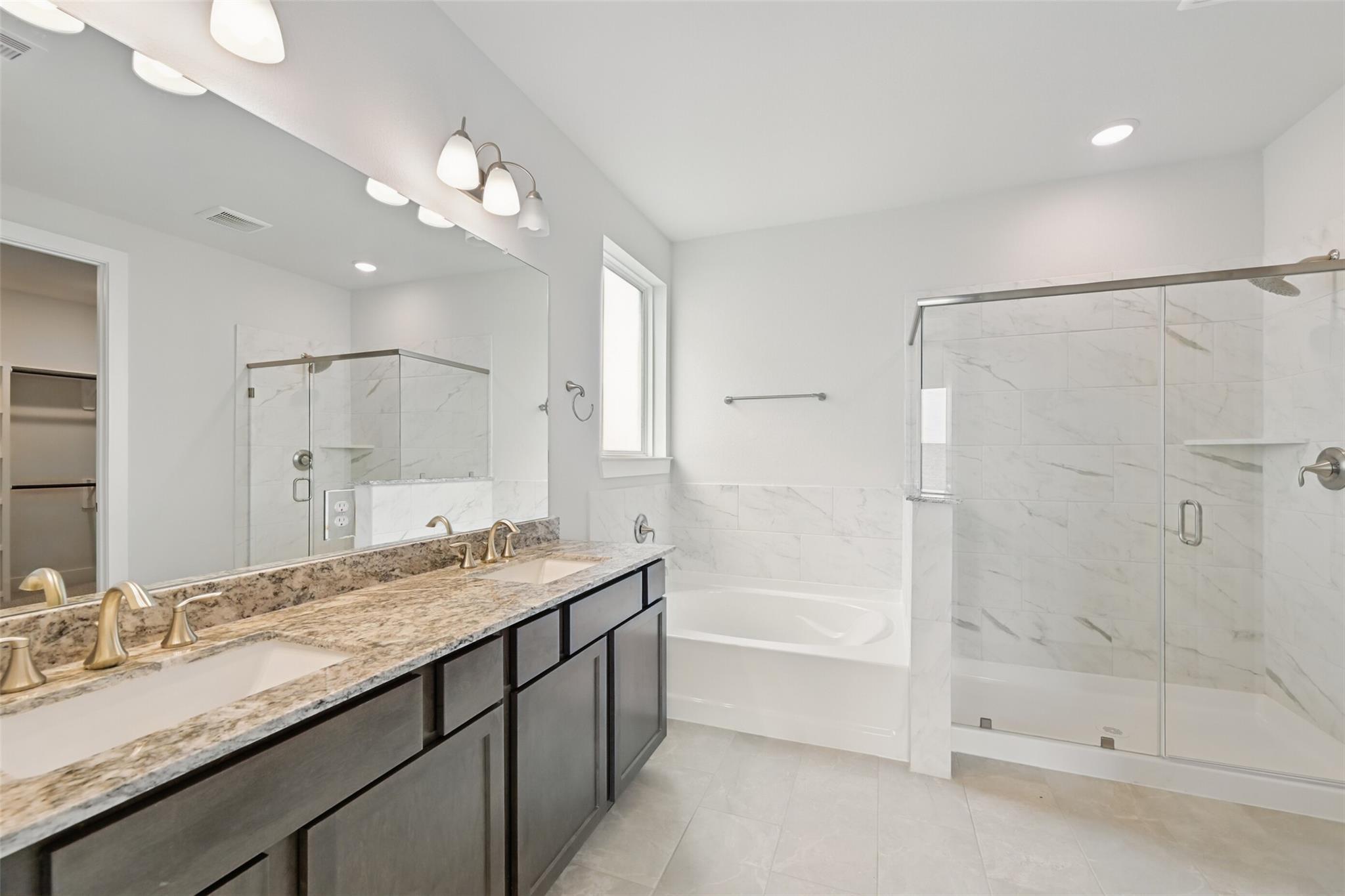 Luxurious master bathroom with double granite vanity, freestanding tub, and glass shower in Davidson Homes The Philip A, Texas City