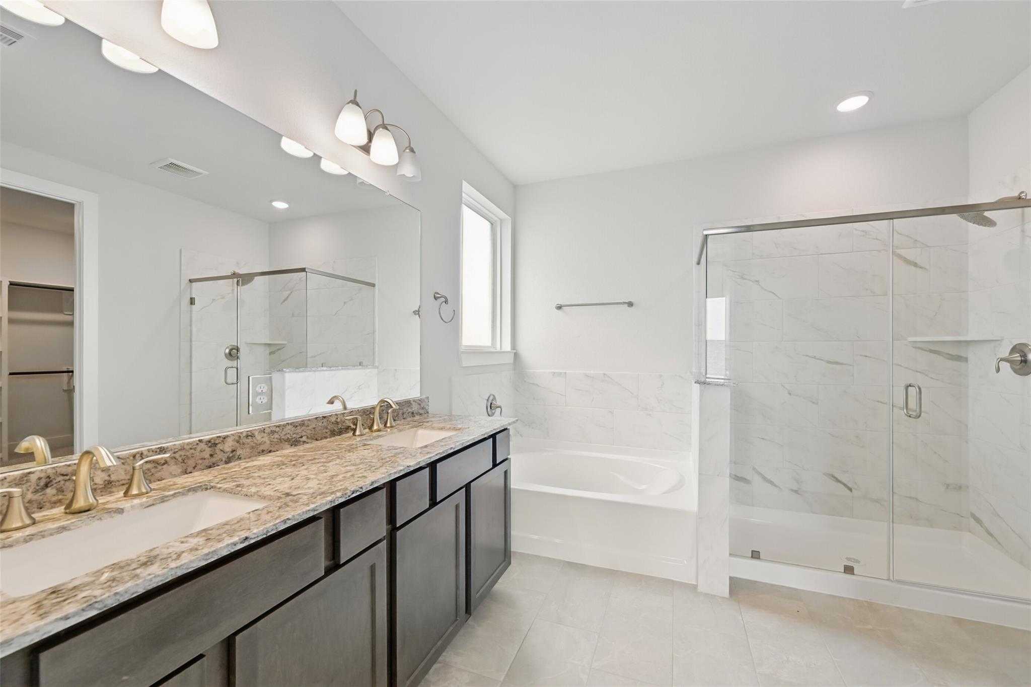 Luxurious master bathroom with double granite vanity, freestanding tub, and glass shower in Davidson Homes The Philip A, Texas City