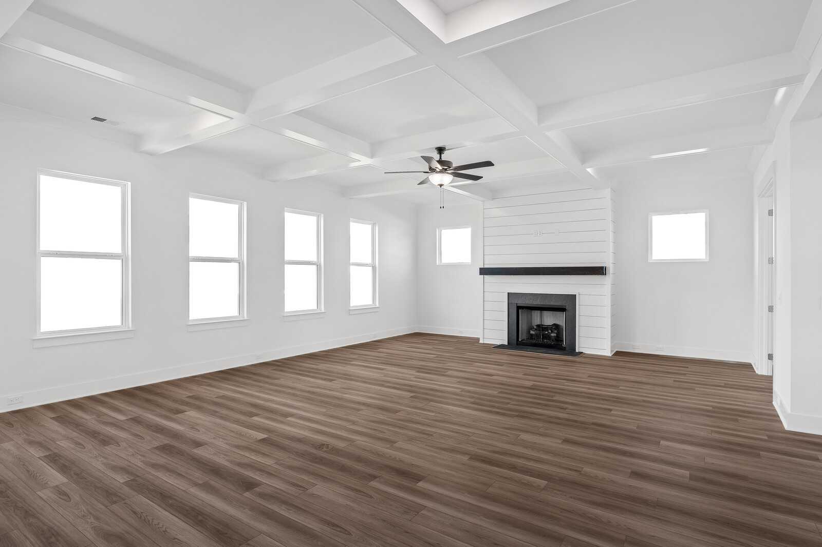 Spacious living room with coffered ceiling, shiplap fireplace, ceiling fan, and large windows in Davidson Homes The Alston A, Murfreesboro, TN