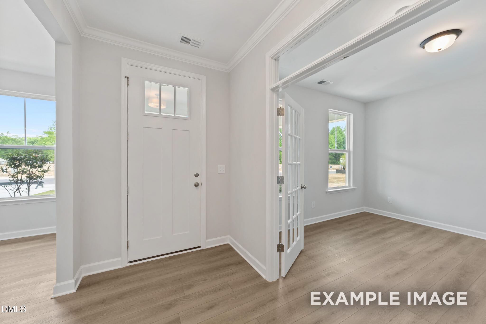 Bright foyer with French doors leading to a home office in The Magnolia B floor plan, Retreat at North Main, Lillington.