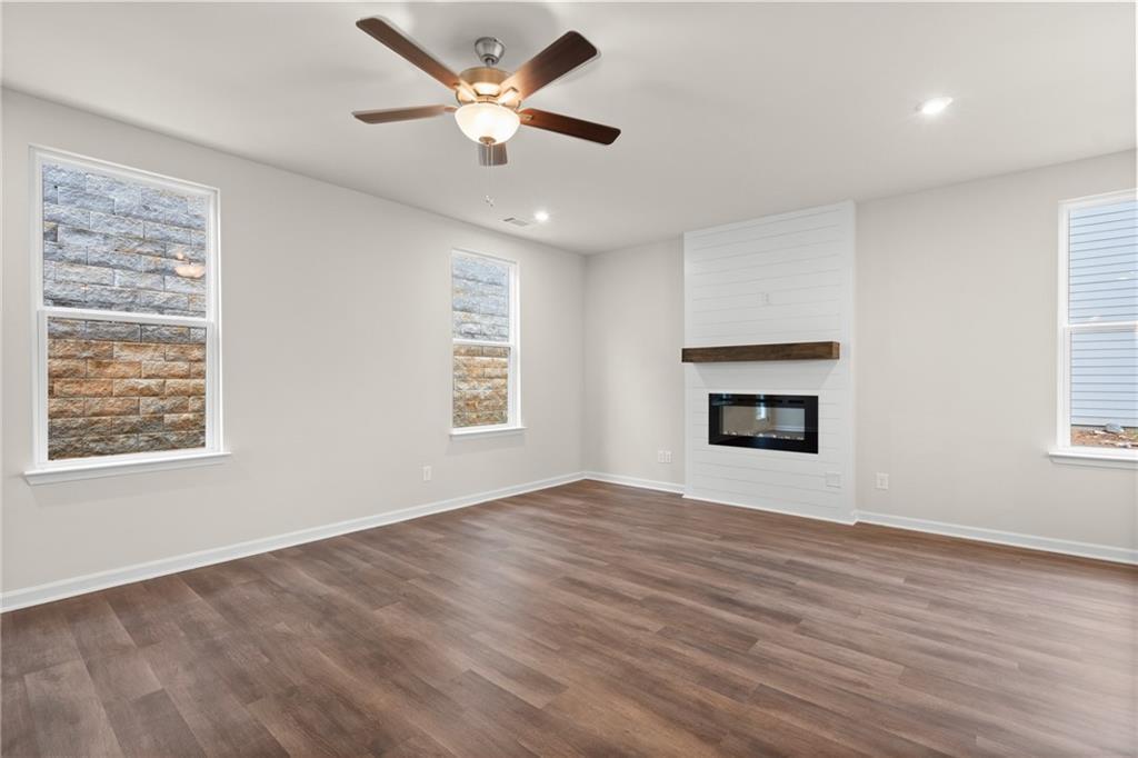 Spacious living room with shiplap fireplace, hardwood floors, ceiling fan, and large windows in Davidson Homes The Marion B, Kennesaw