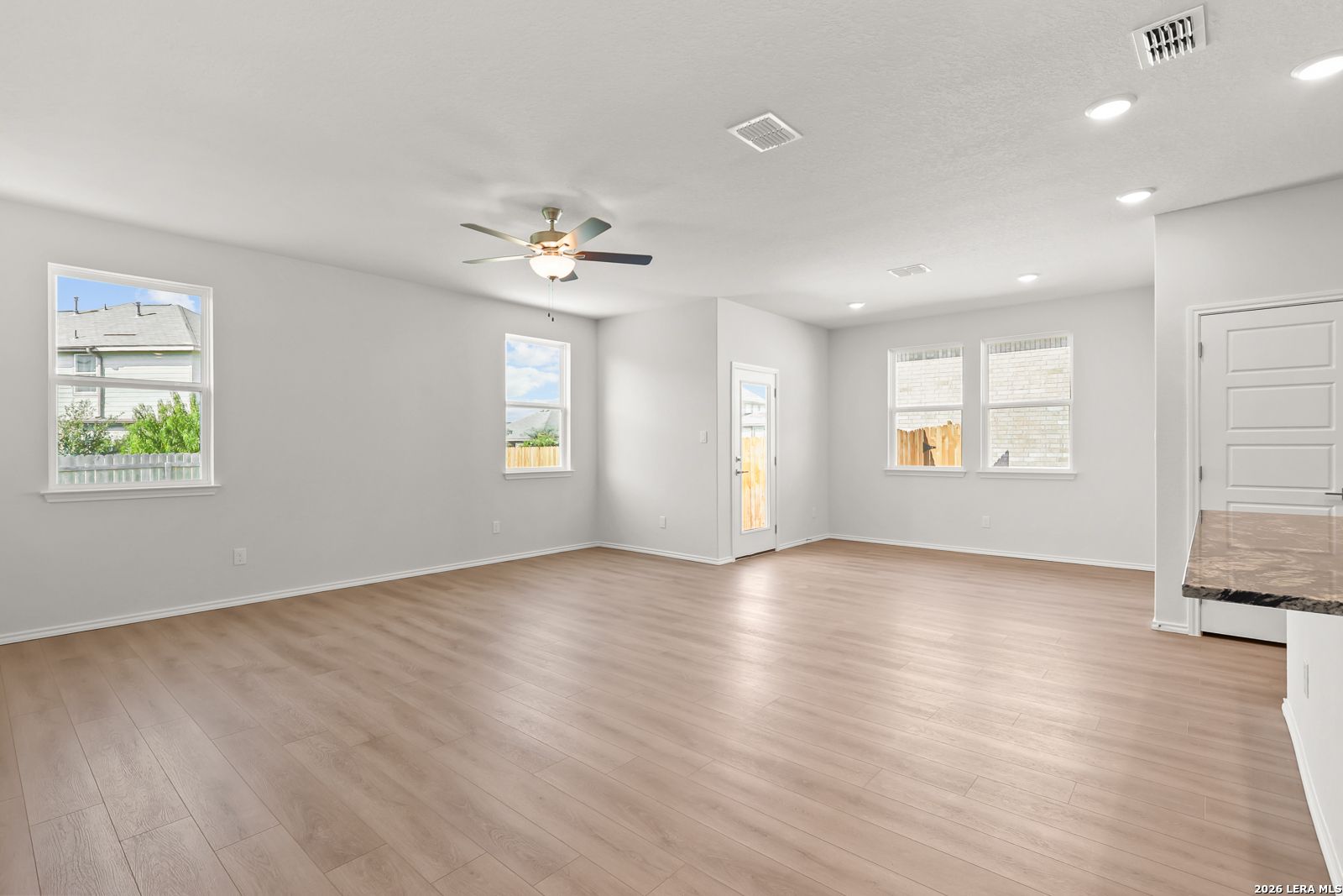 Bright open-concept living area with wood-look flooring and ceiling fan in The Daphne I floor plan by Davidson Homes, Bricewood San Antonio