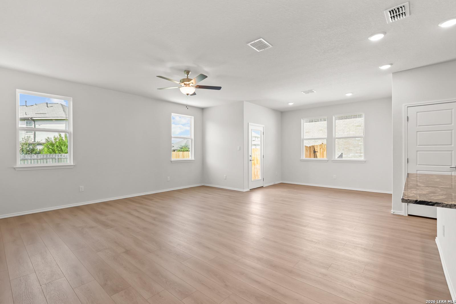 Bright open-concept living area with wood-look flooring and ceiling fan in The Daphne I floor plan by Davidson Homes, Bricewood San Antonio