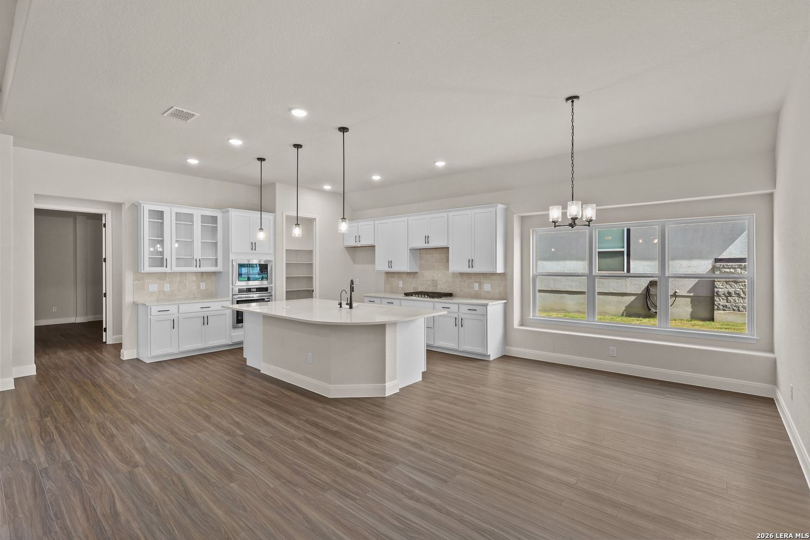 Modern white kitchen with large island and breakfast nook in The Summerlin B home for sale in Potranco Oaks, Castroville.