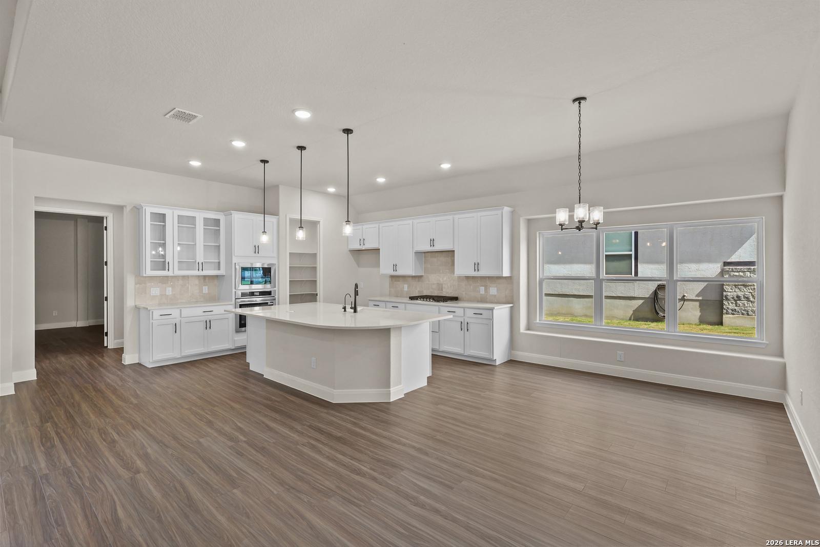 Modern white kitchen with large island and breakfast nook in The Summerlin B home for sale in Potranco Oaks, Castroville.
