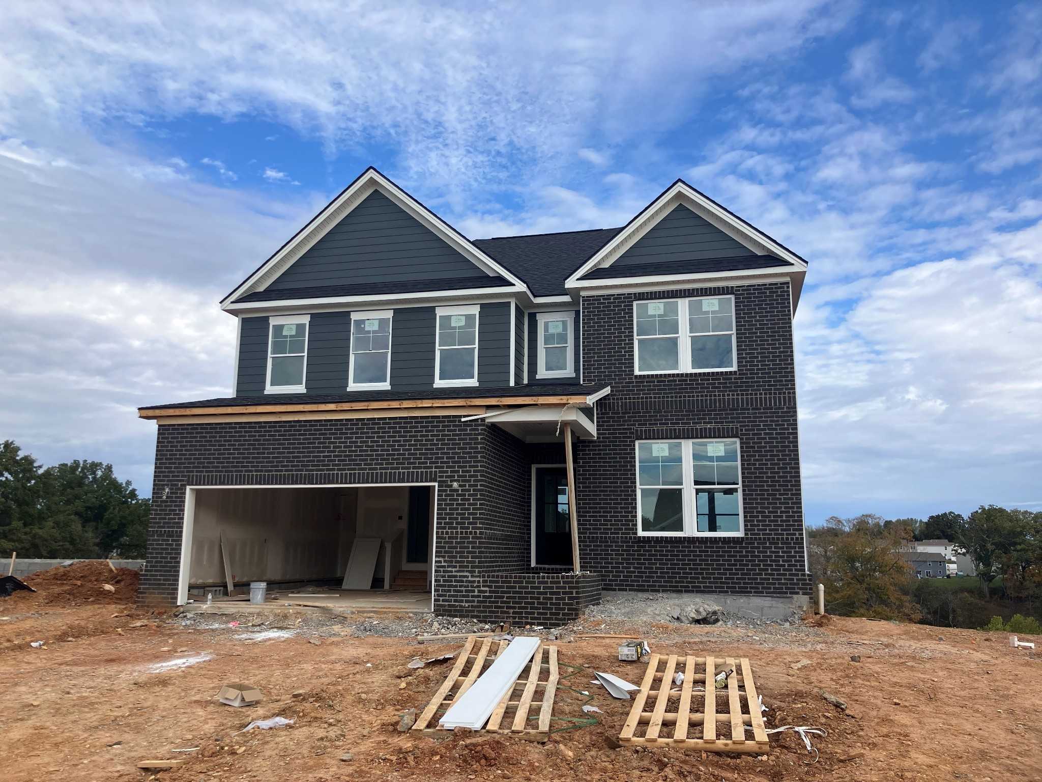 Two-story Willow C home by Davidson Homes with dark gray siding, brick base, open 2-car garage on construction site in Calista Farms, White House, TN