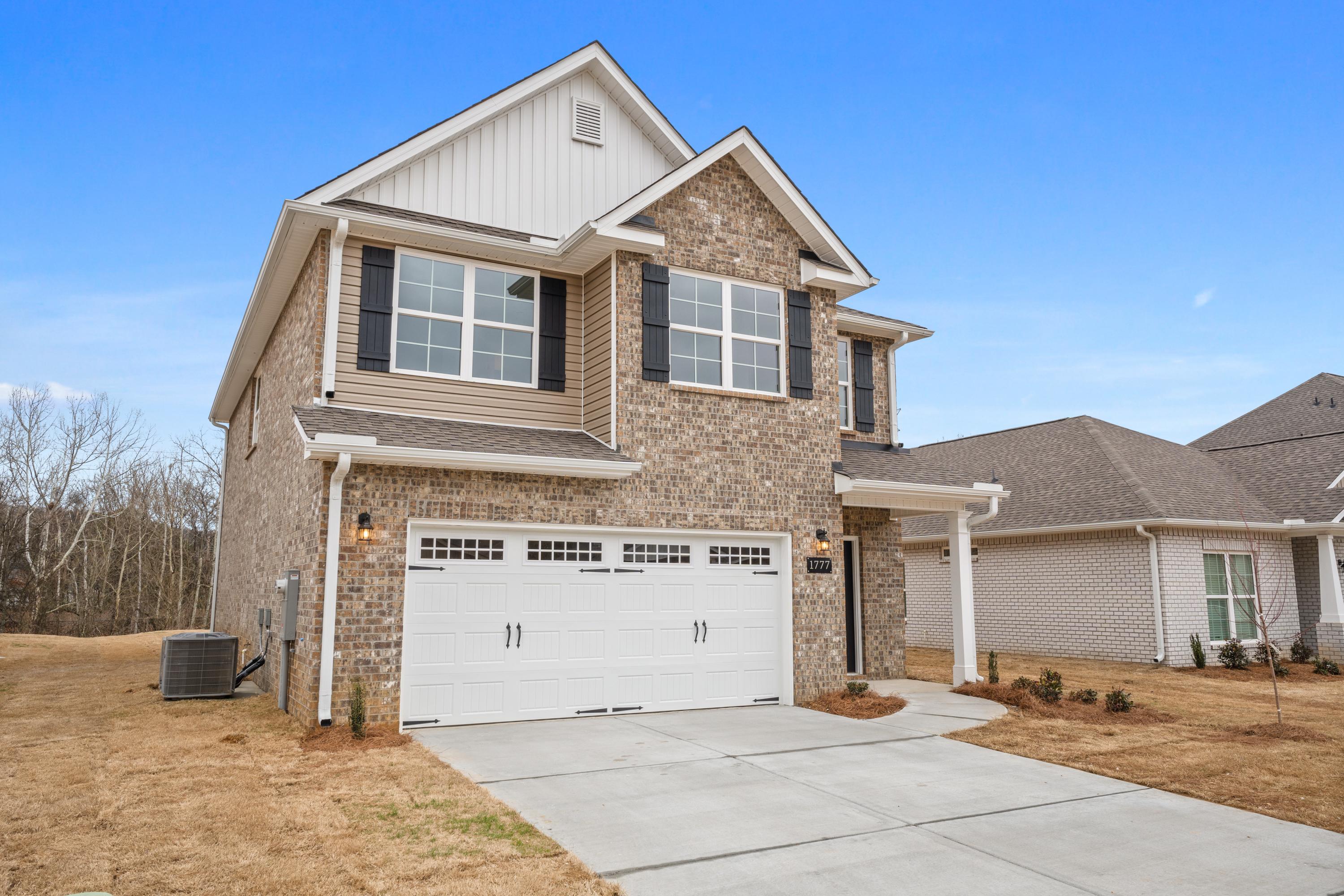 Two-story Aiken home elevation by Davidson Homes featuring beige brick stone facade, two-car garage, and front porch in Meridianville AL