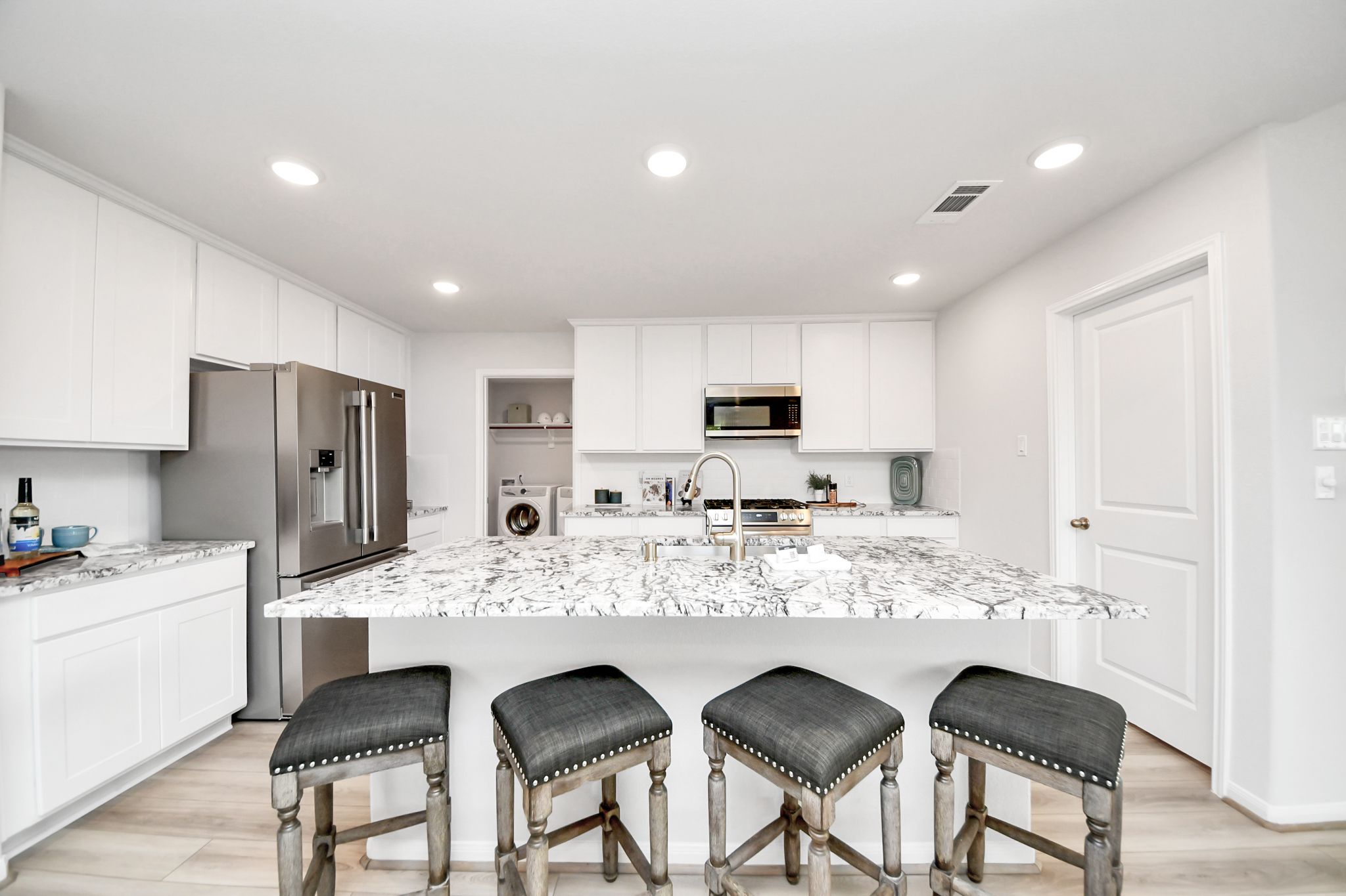 Modern kitchen with white cabinets, granite island, and bar seating at Sunterra in Katy, Texas by Davidson Homes.